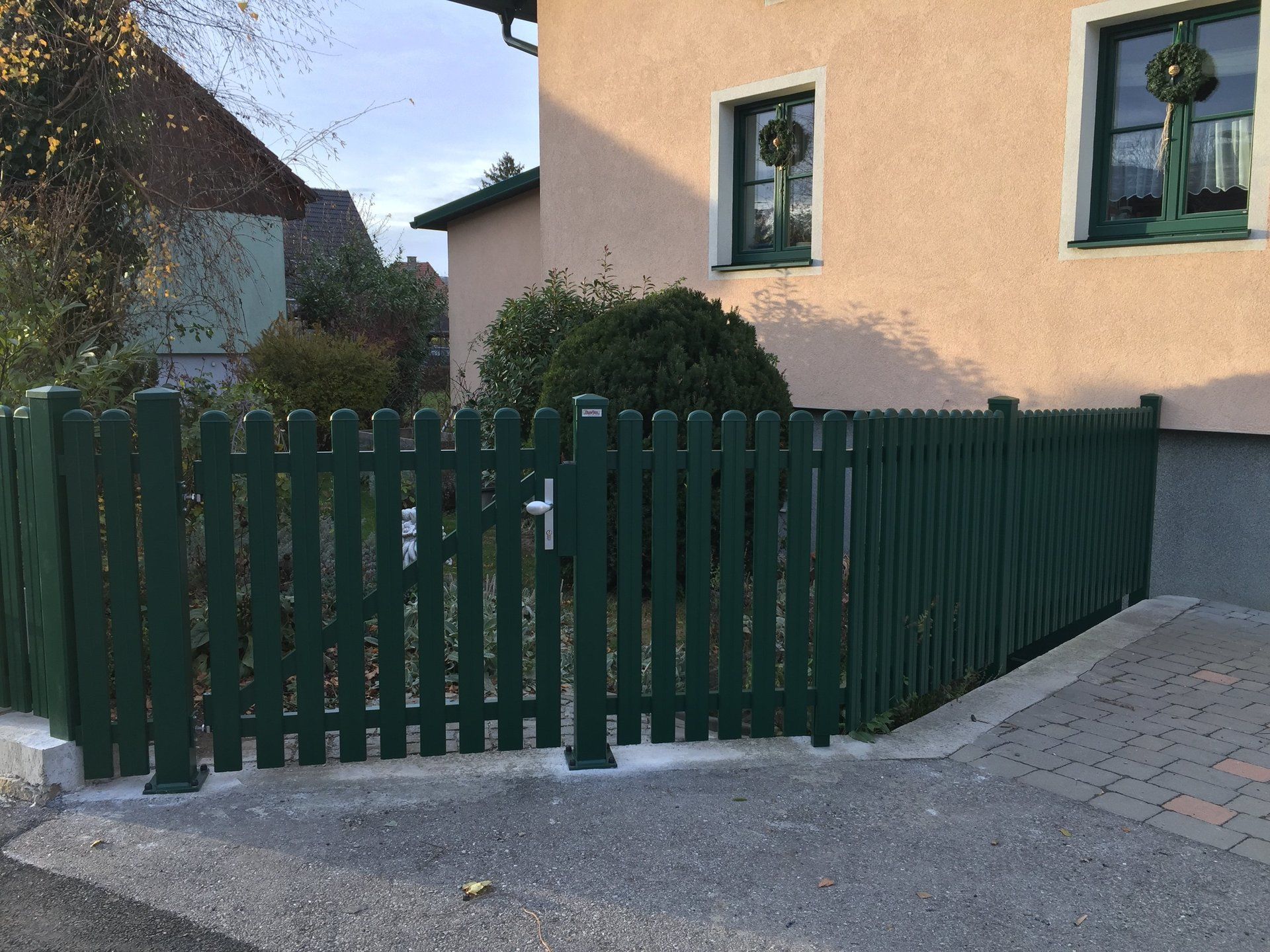 Ein grüner Zaun mit einem Tor vor einem Haus