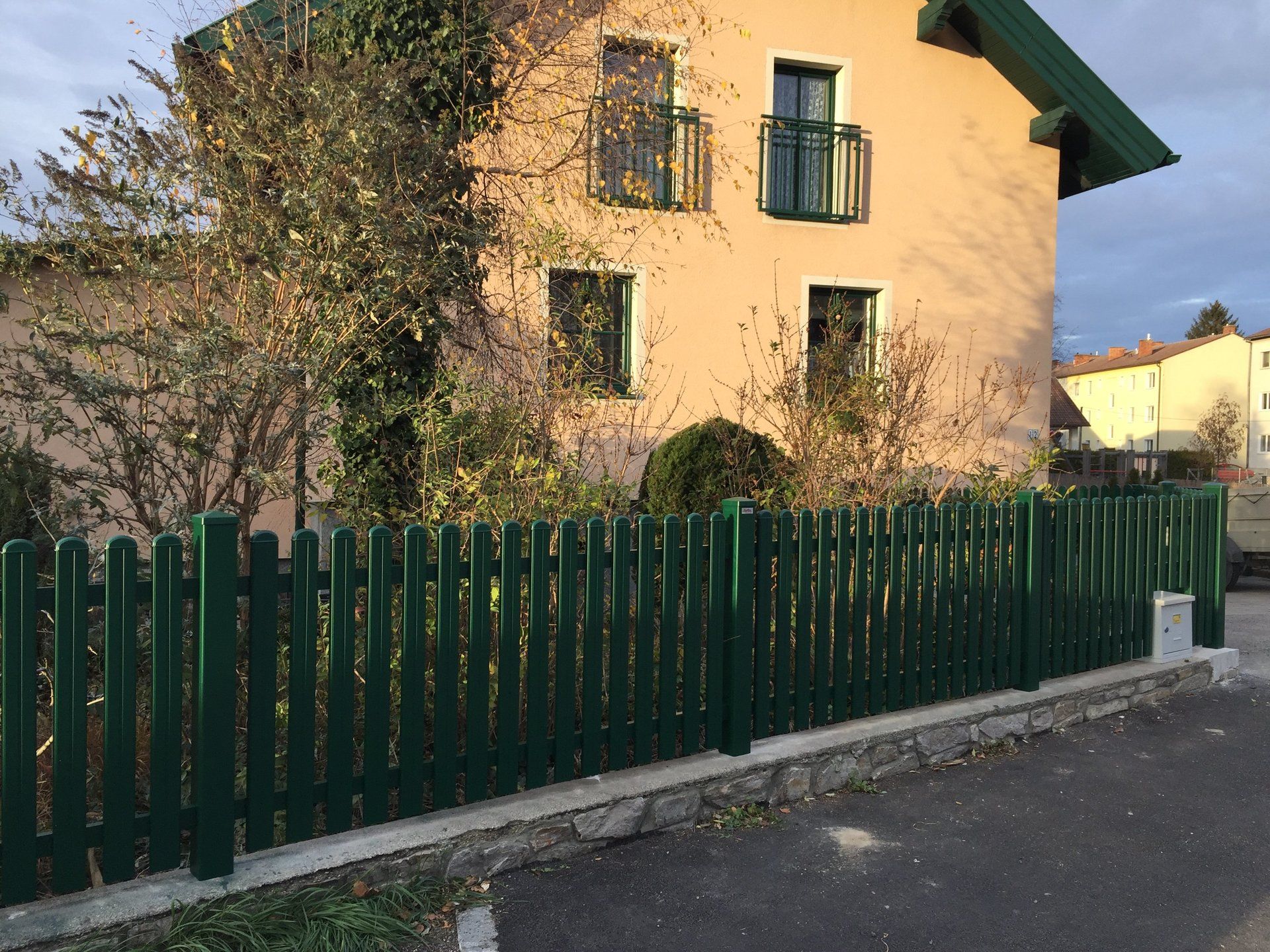 Ein Haus mit einem grünen Zaun davor