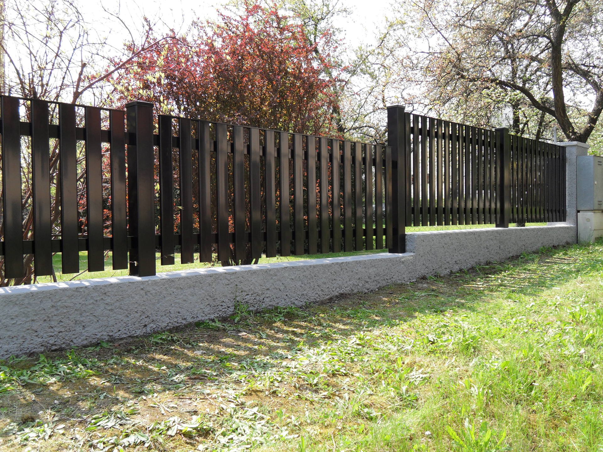 Ein Holzzaun ist von Gras und Bäumen umgeben