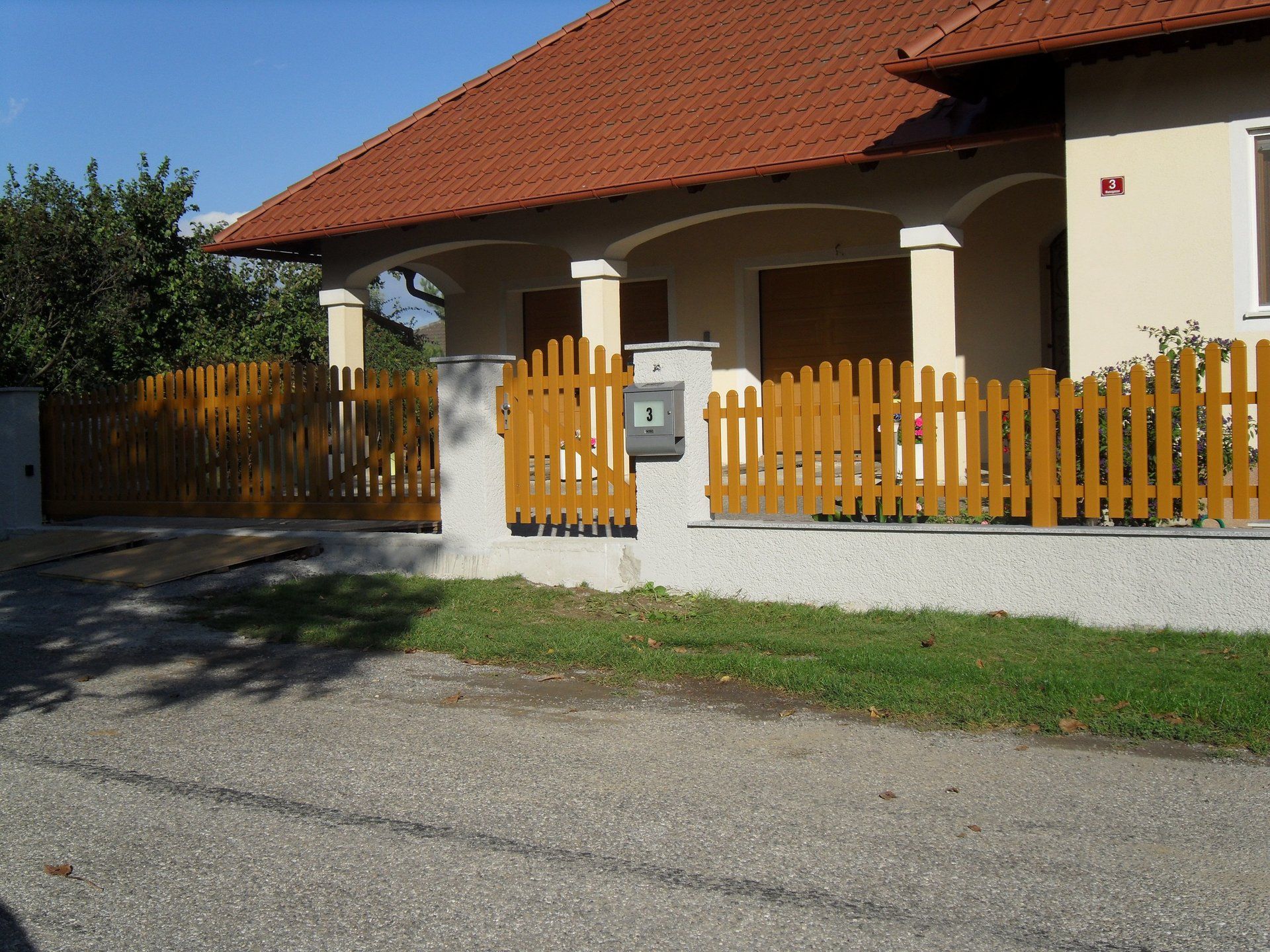 Ein Haus mit einem Holzzaun und einem Briefkasten davor