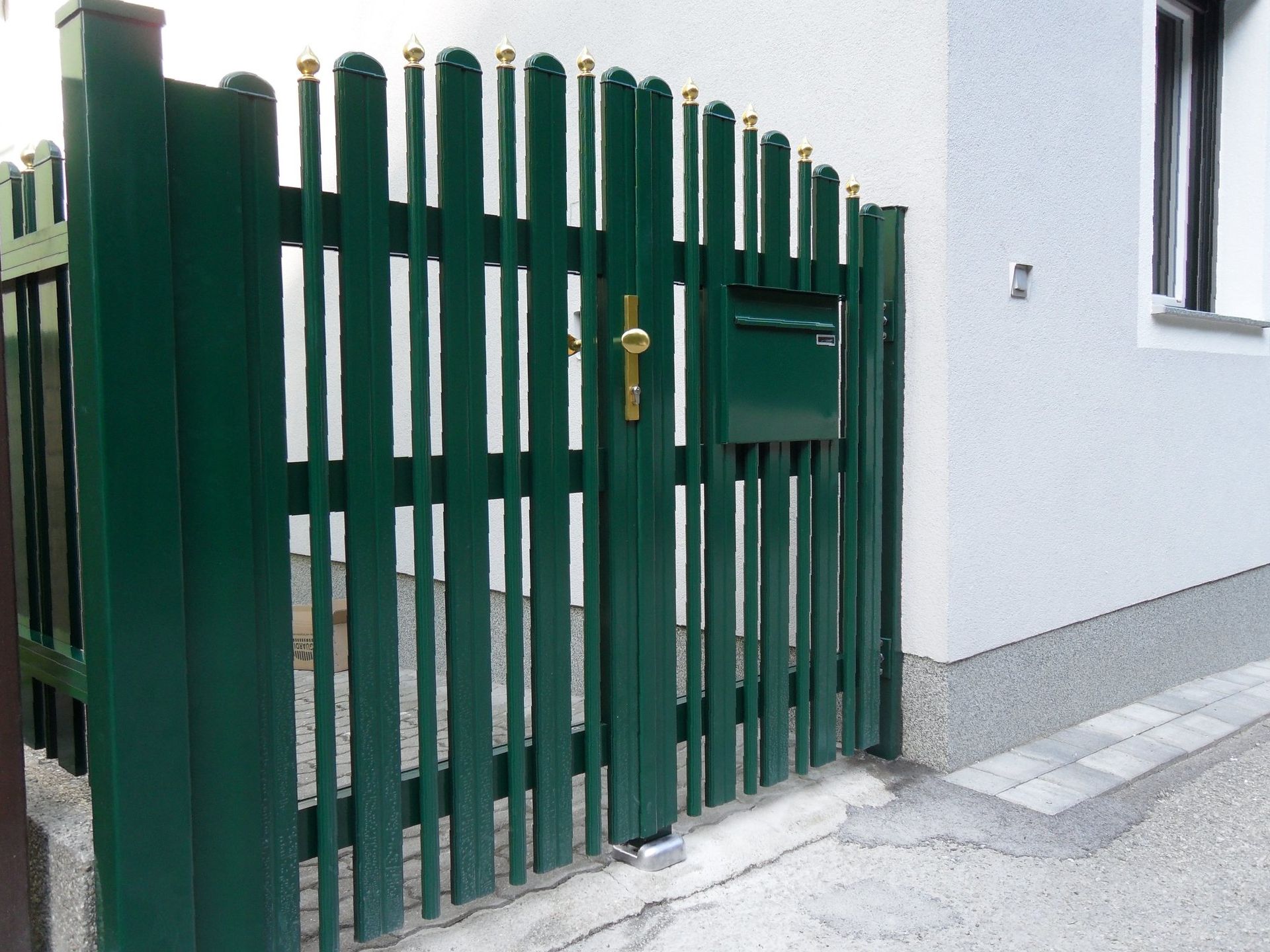 Ein grüner Zaun mit einem daran befestigten Briefkasten