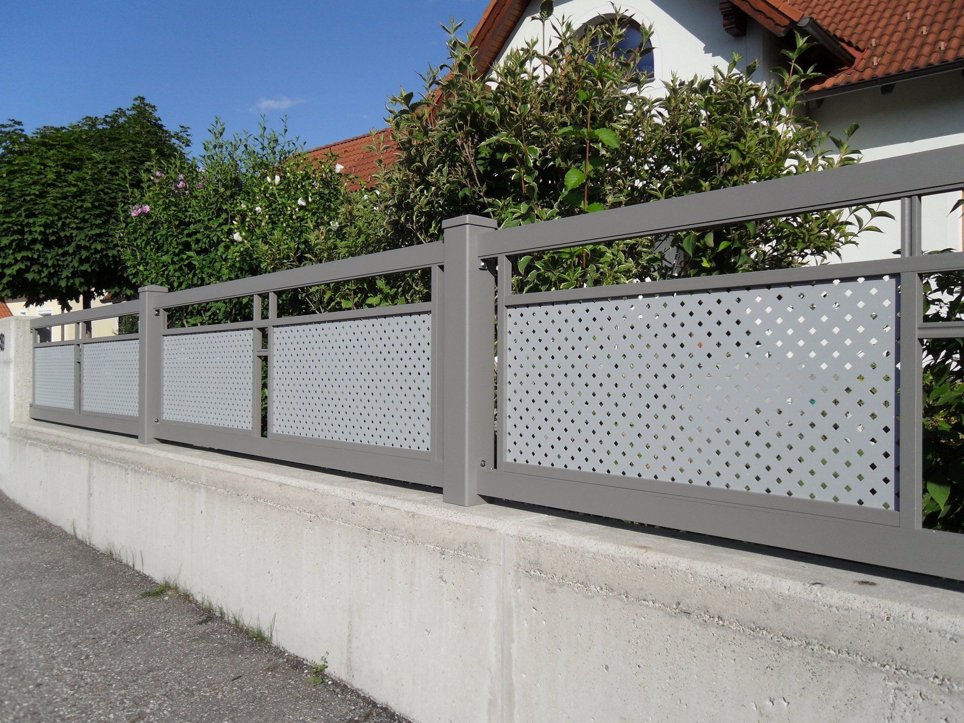 Ein Zaun mit Löchern darin steht neben einem Haus