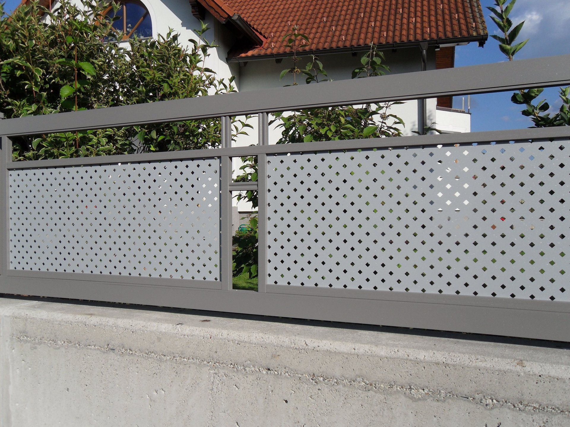 Ein Zaun mit Löchern darin und ein Haus im Hintergrund