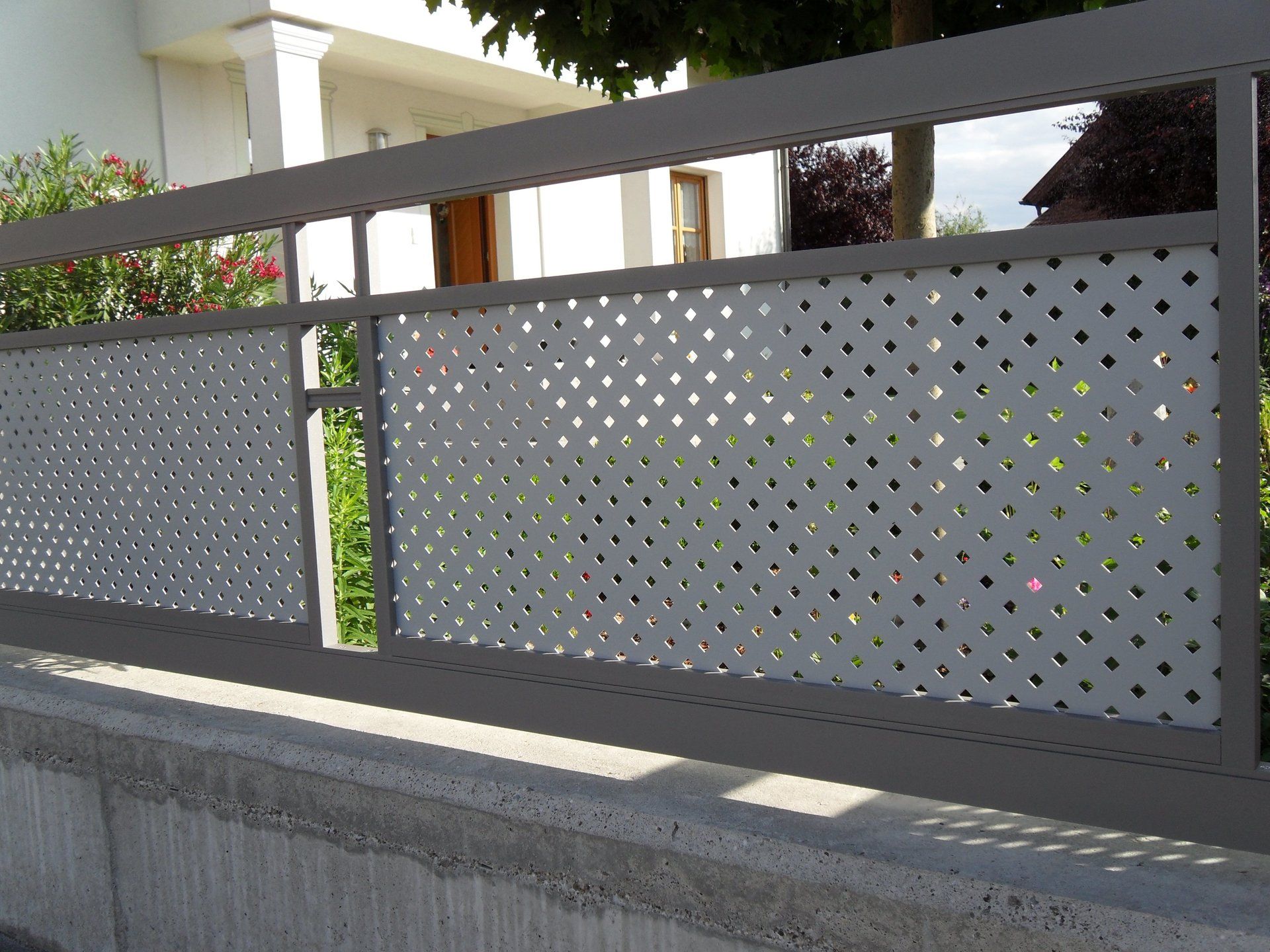 Ein Zaun mit Löchern darin und ein Haus im Hintergrund