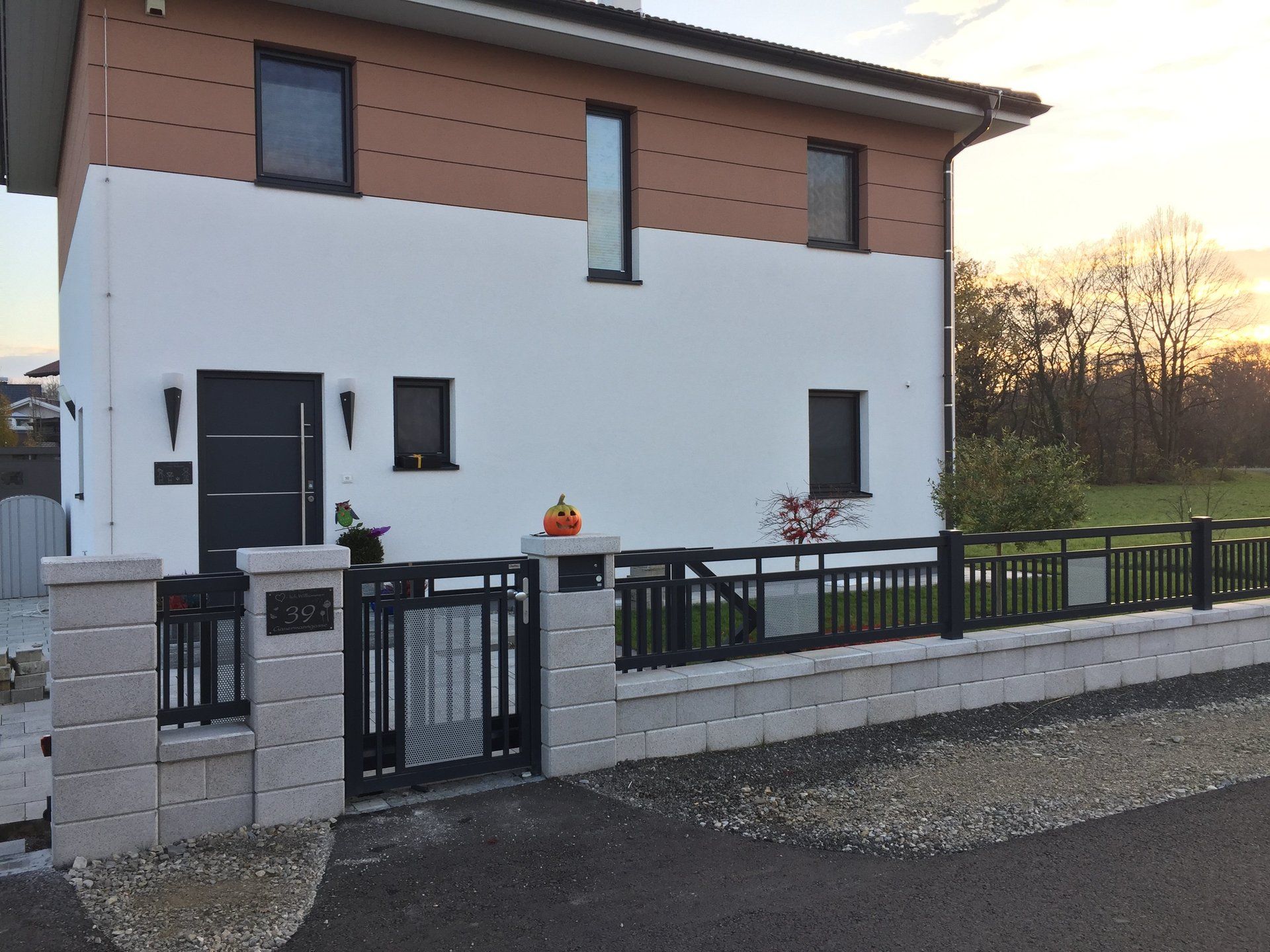 Ein weißes Haus mit einem schwarzen Zaun und einem Kürbis davor