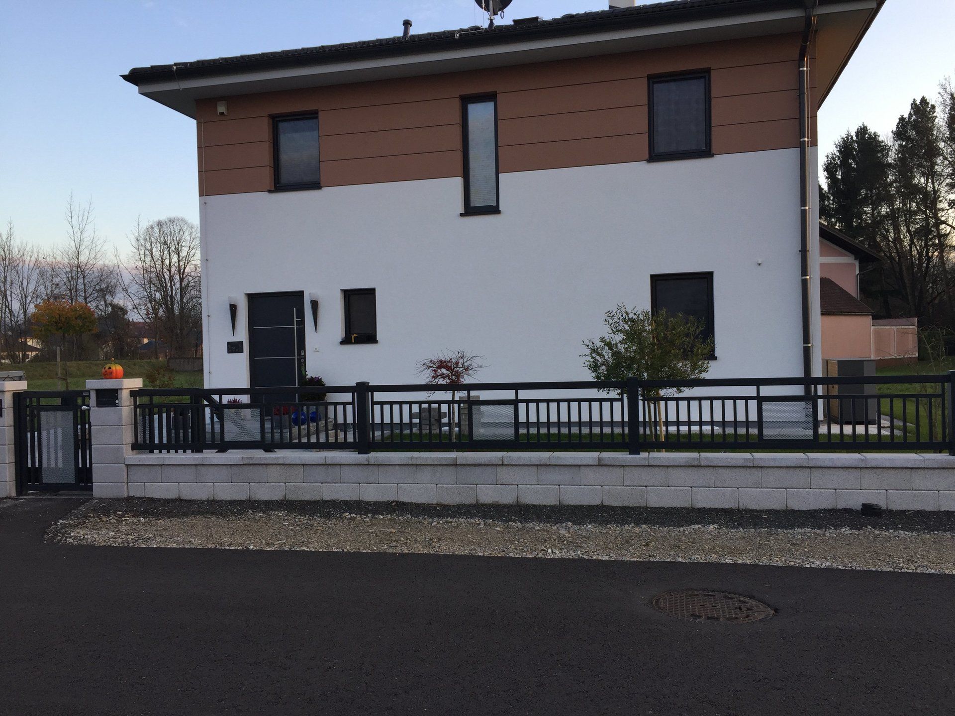 Ein weißes Haus mit einem schwarzen Zaun davor