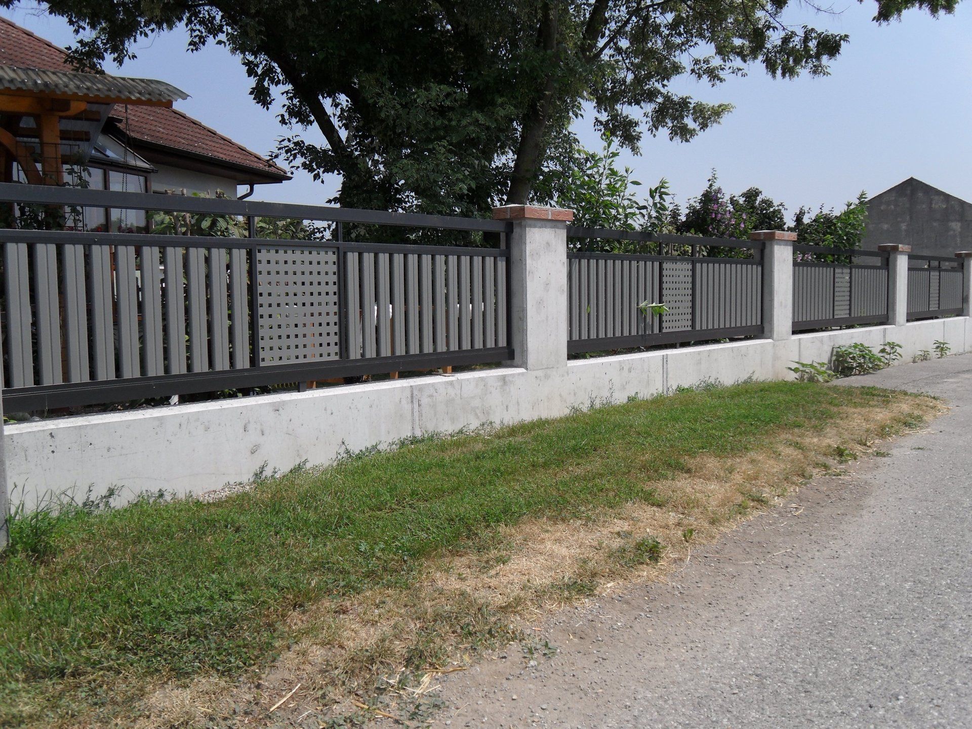 Ein Zaun am Straßenrand mit einem Haus im Hintergrund