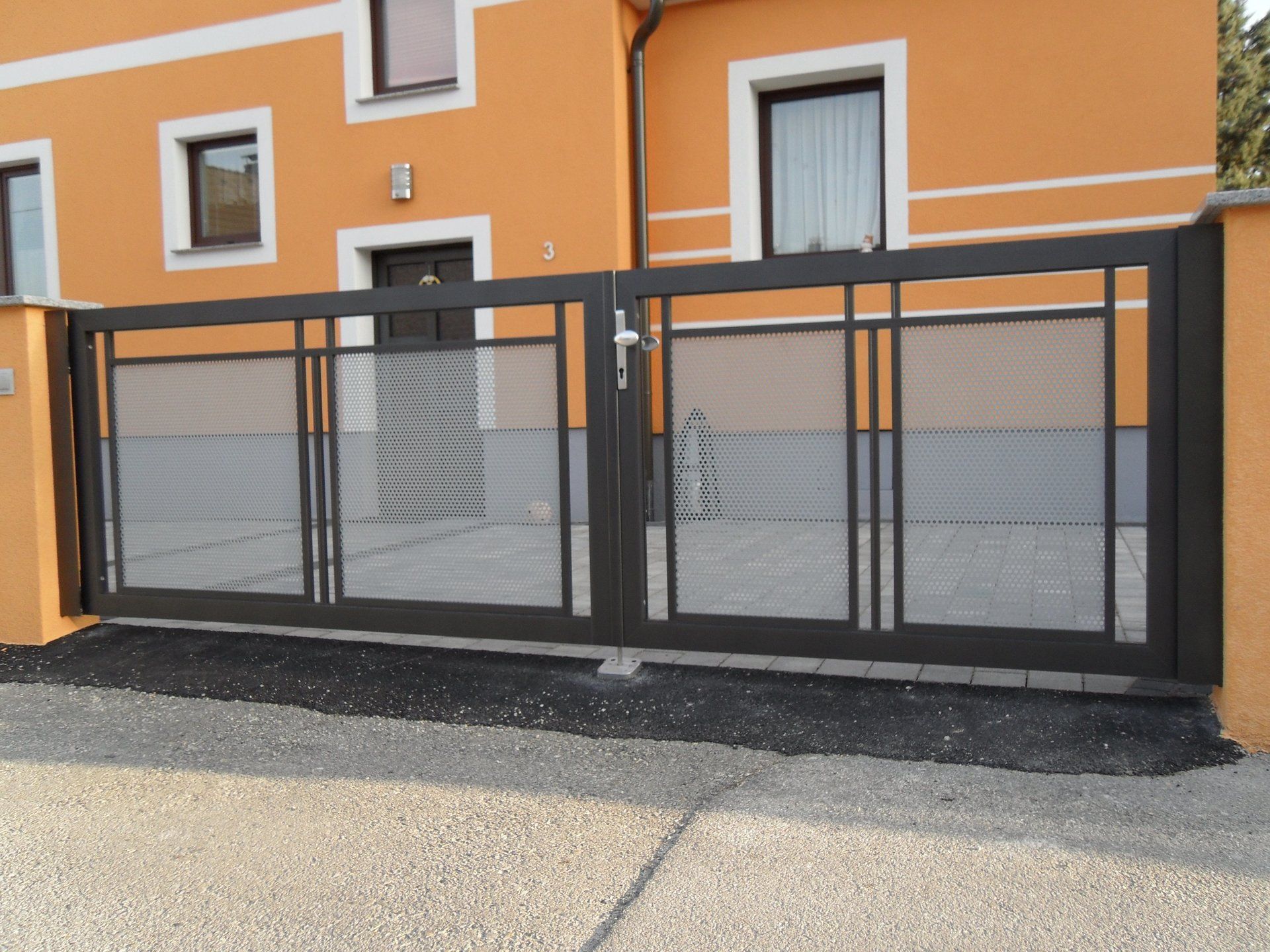 Ein orangefarbenes Haus mit einem schwarzen Tor davor