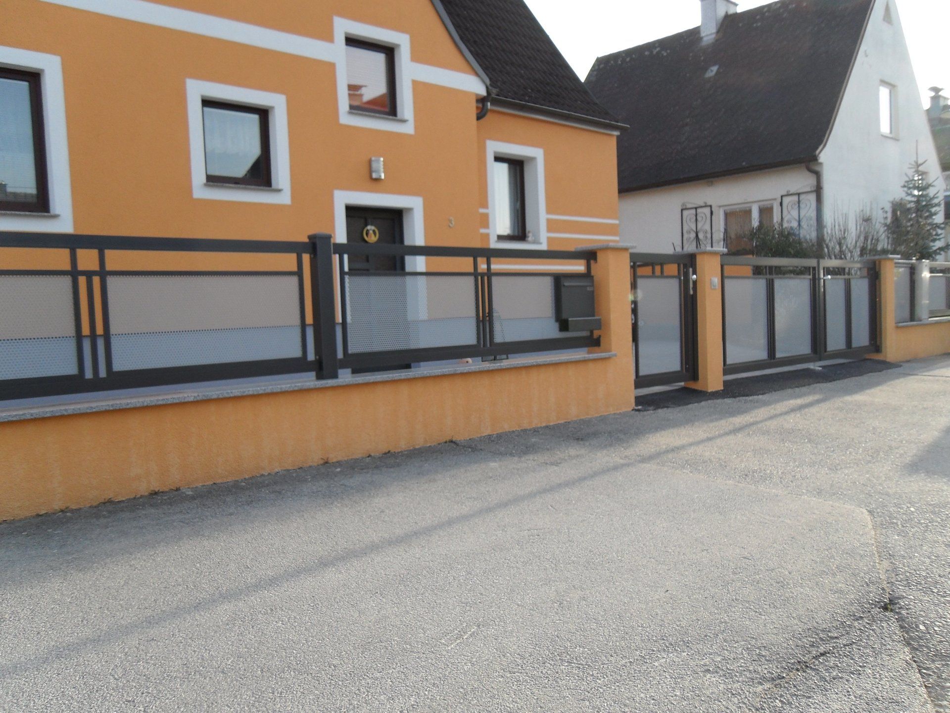 Ein gelbes Haus mit einem schwarzen Zaun davor