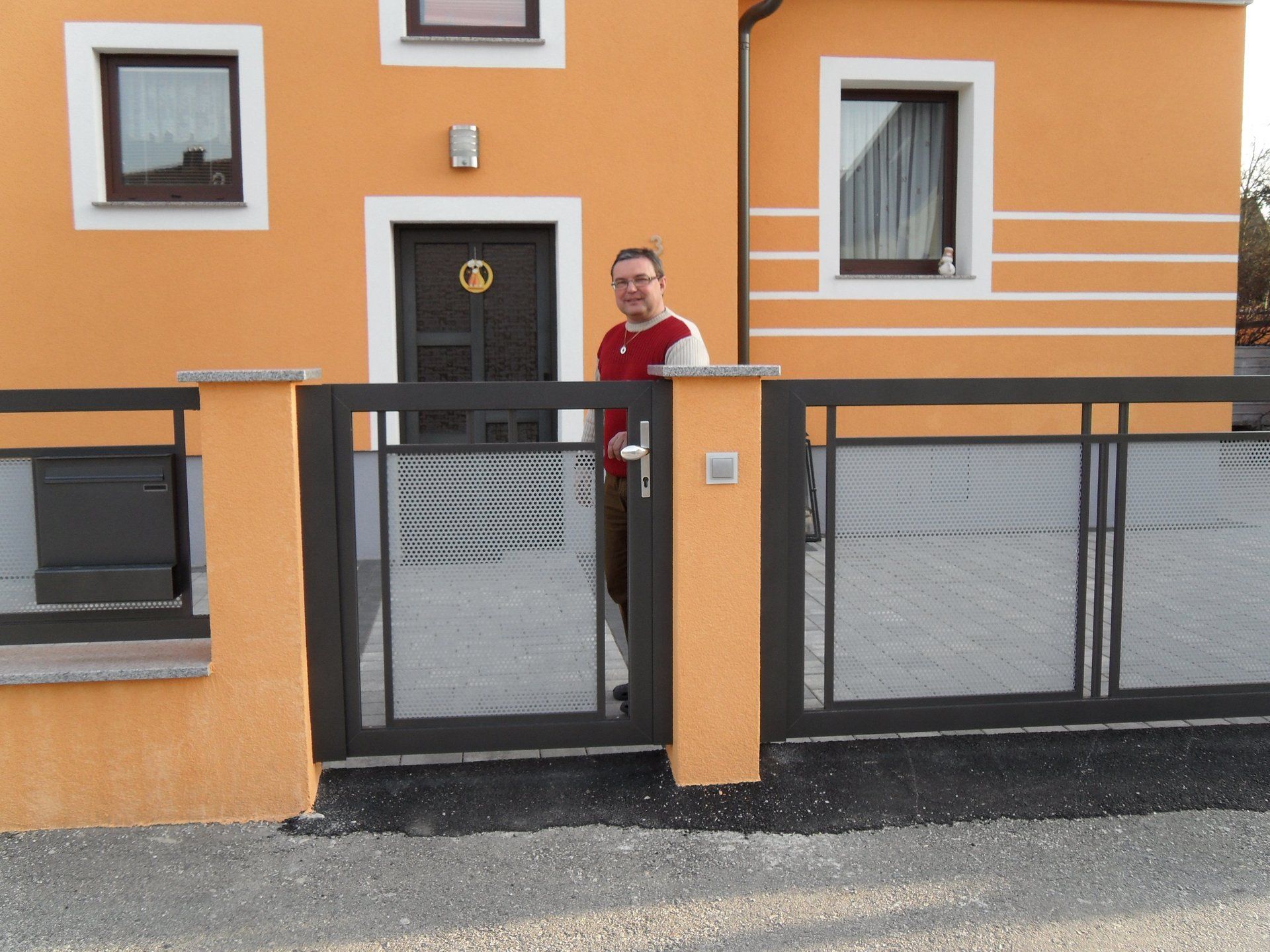 Ein Mann steht vor einem orangefarbenen Haus