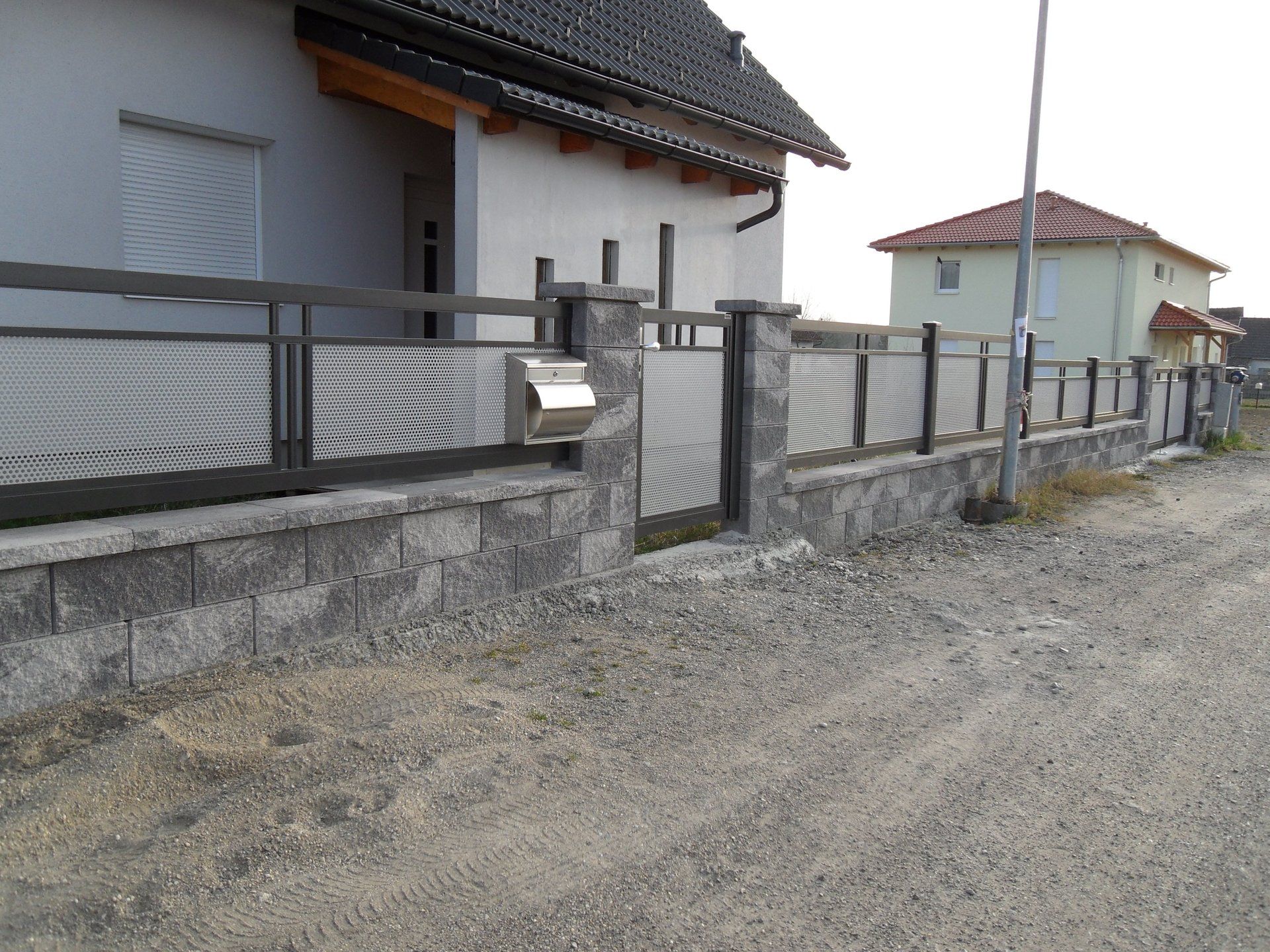 Ein Zaun mit einem Briefkasten vor einem Haus