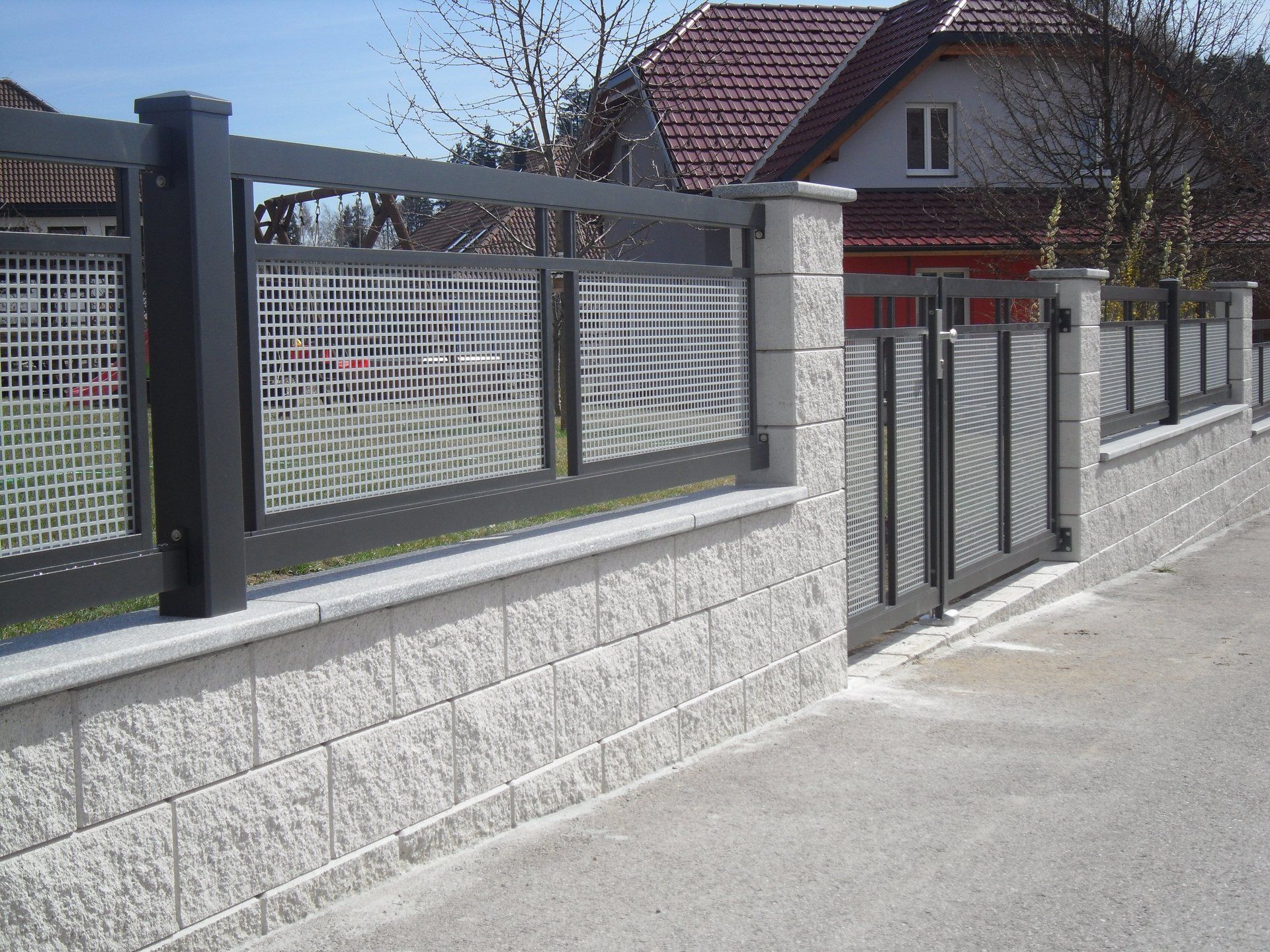 Eine Backsteinmauer mit einem Metallzaun und einem Tor