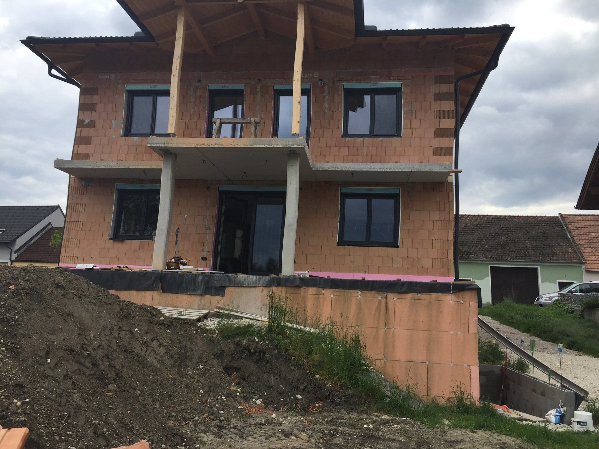 Auf einem Hügel wird ein Backsteinhaus gebaut.