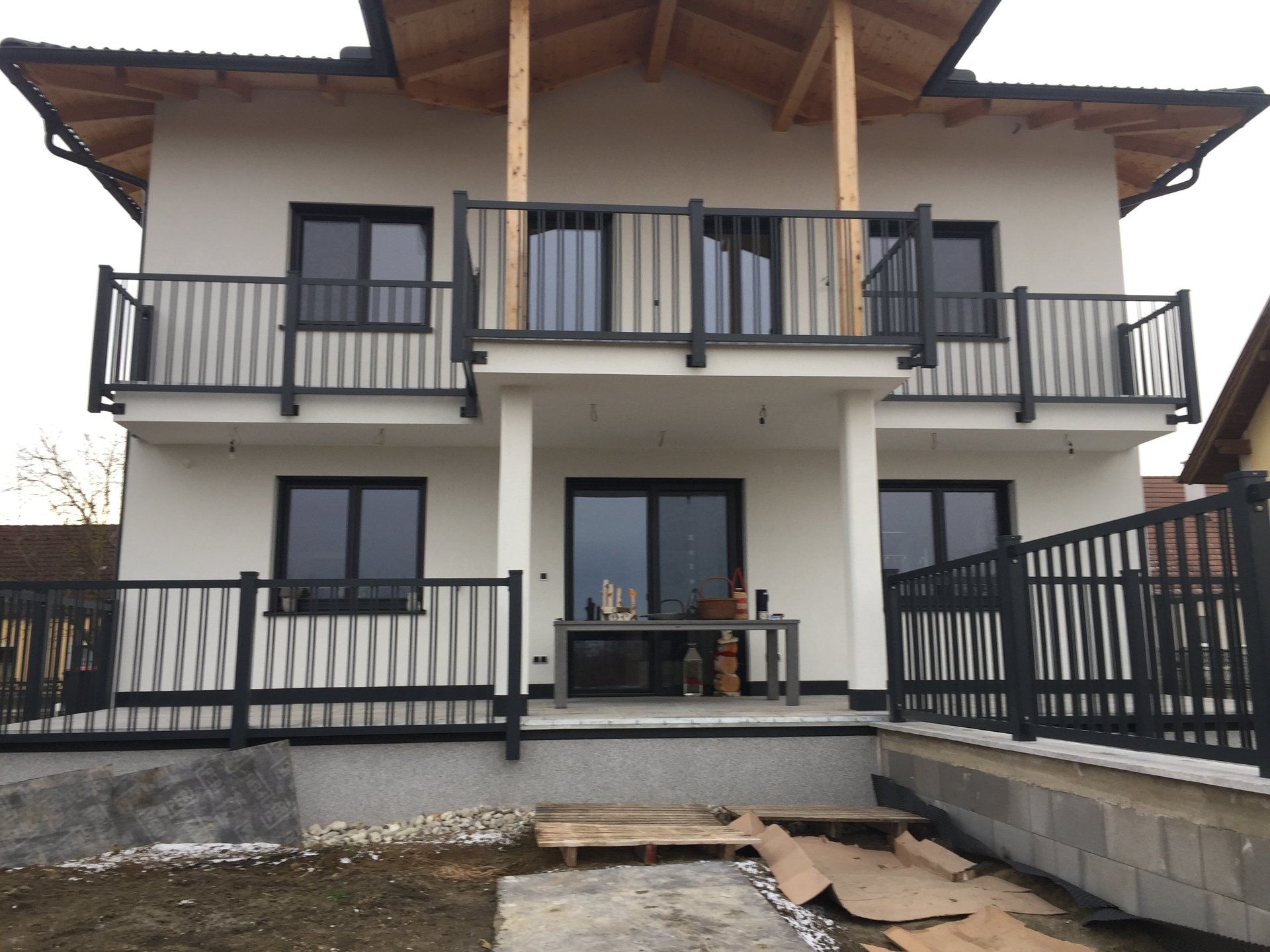 Ein weißes Haus mit einem Balkon und einem schwarzen Geländer