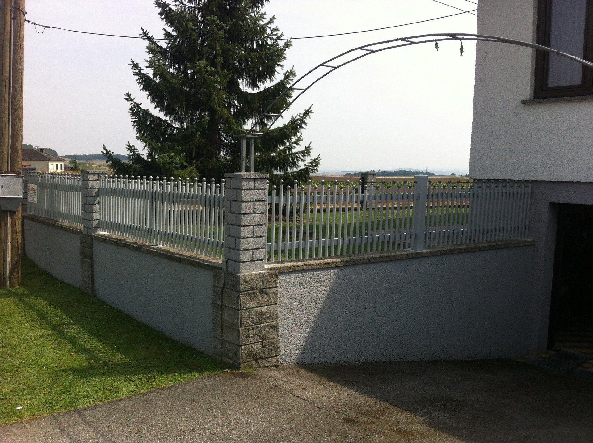 Ein weißes Haus mit einem Zaun darum und einem Baum im Hintergrund