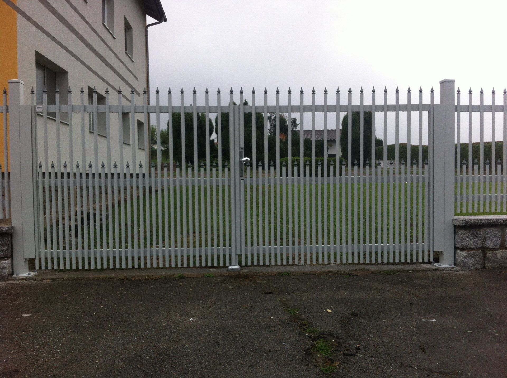 Ein weißer Zaun mit einem gelben Gebäude im Hintergrund