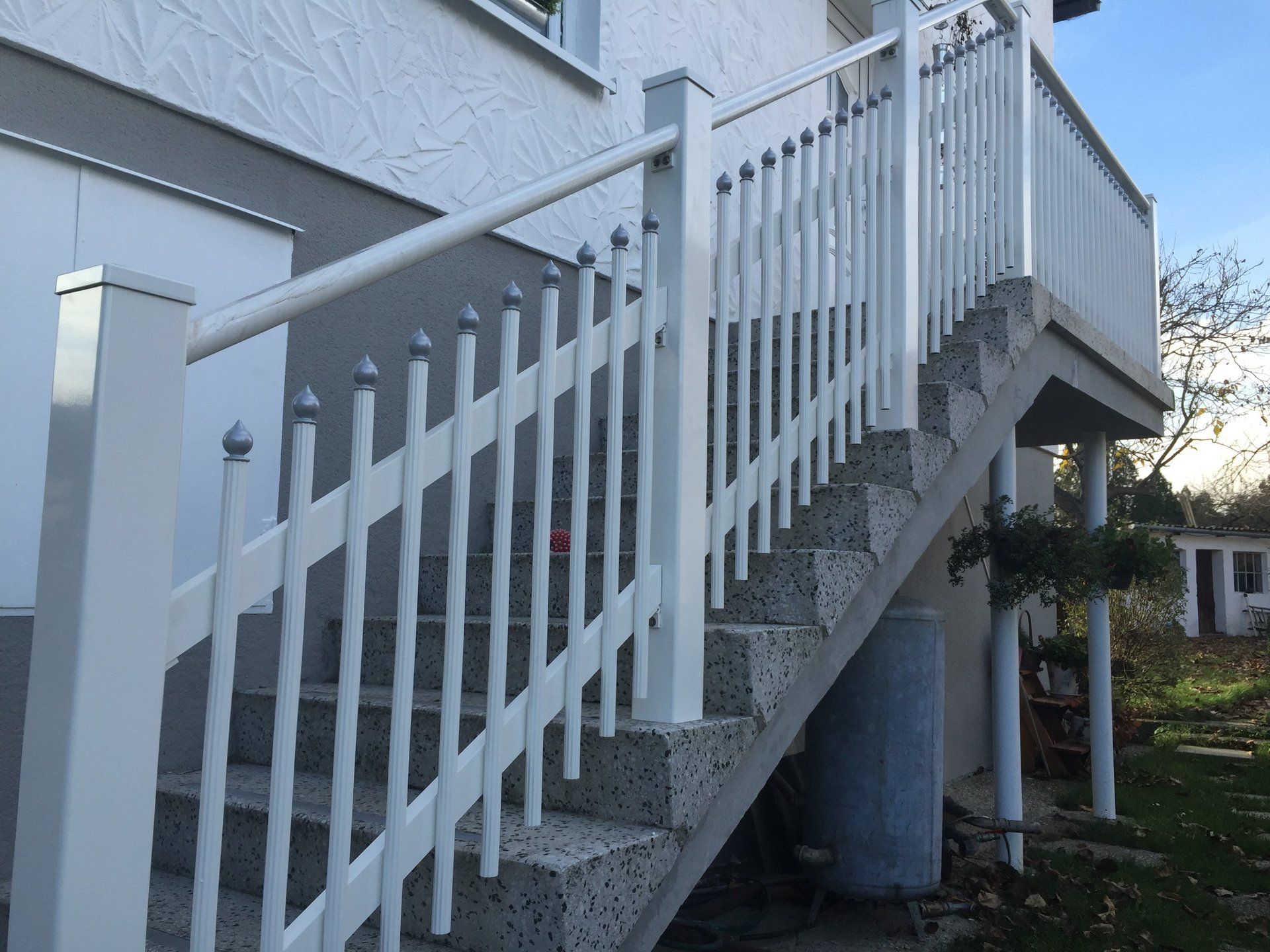 Ein weißes Geländer umgibt eine Treppe, die zu einem Haus hinaufführt