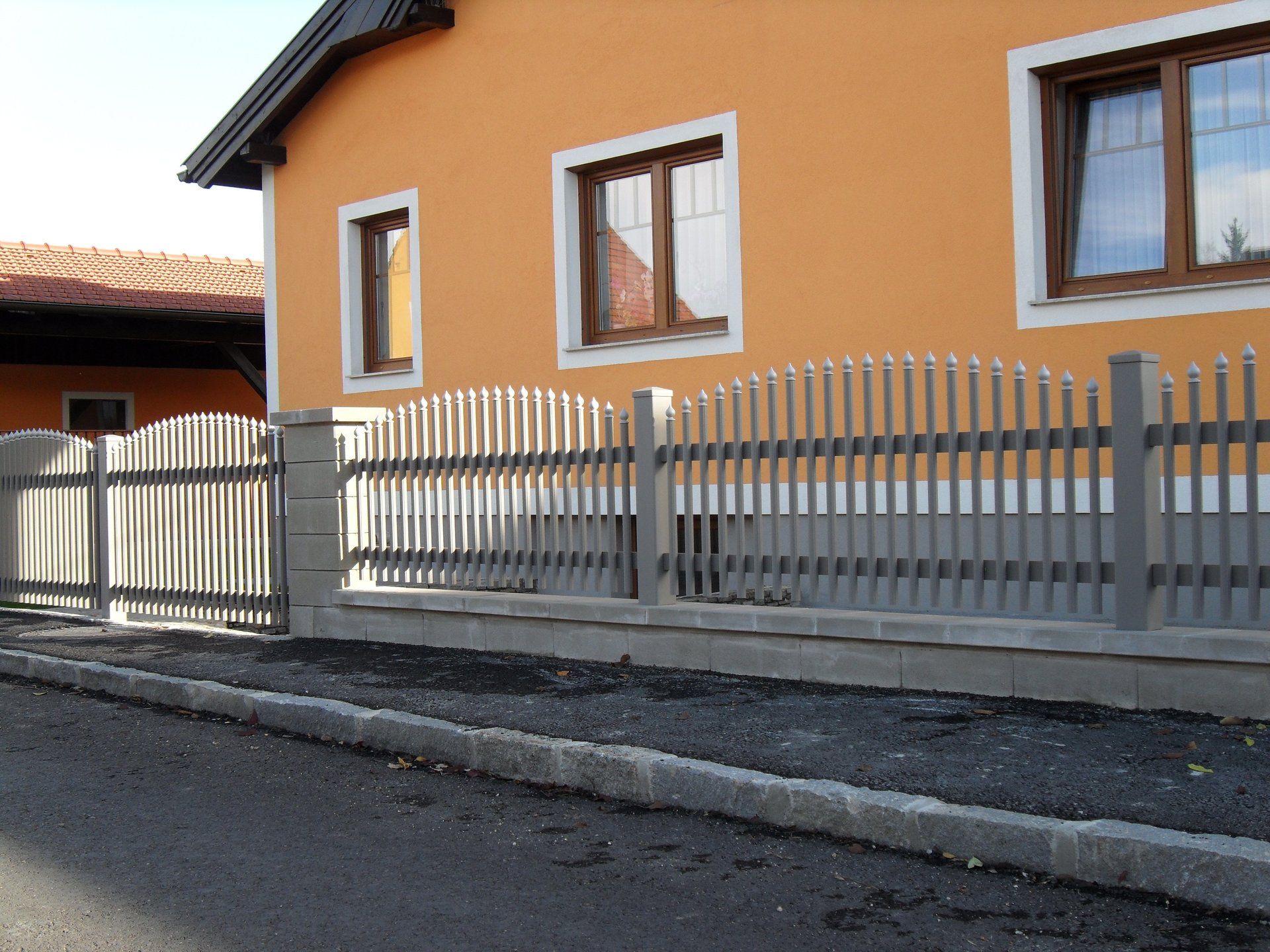 Ein orangefarbenes Haus mit einem weißen Zaun davor