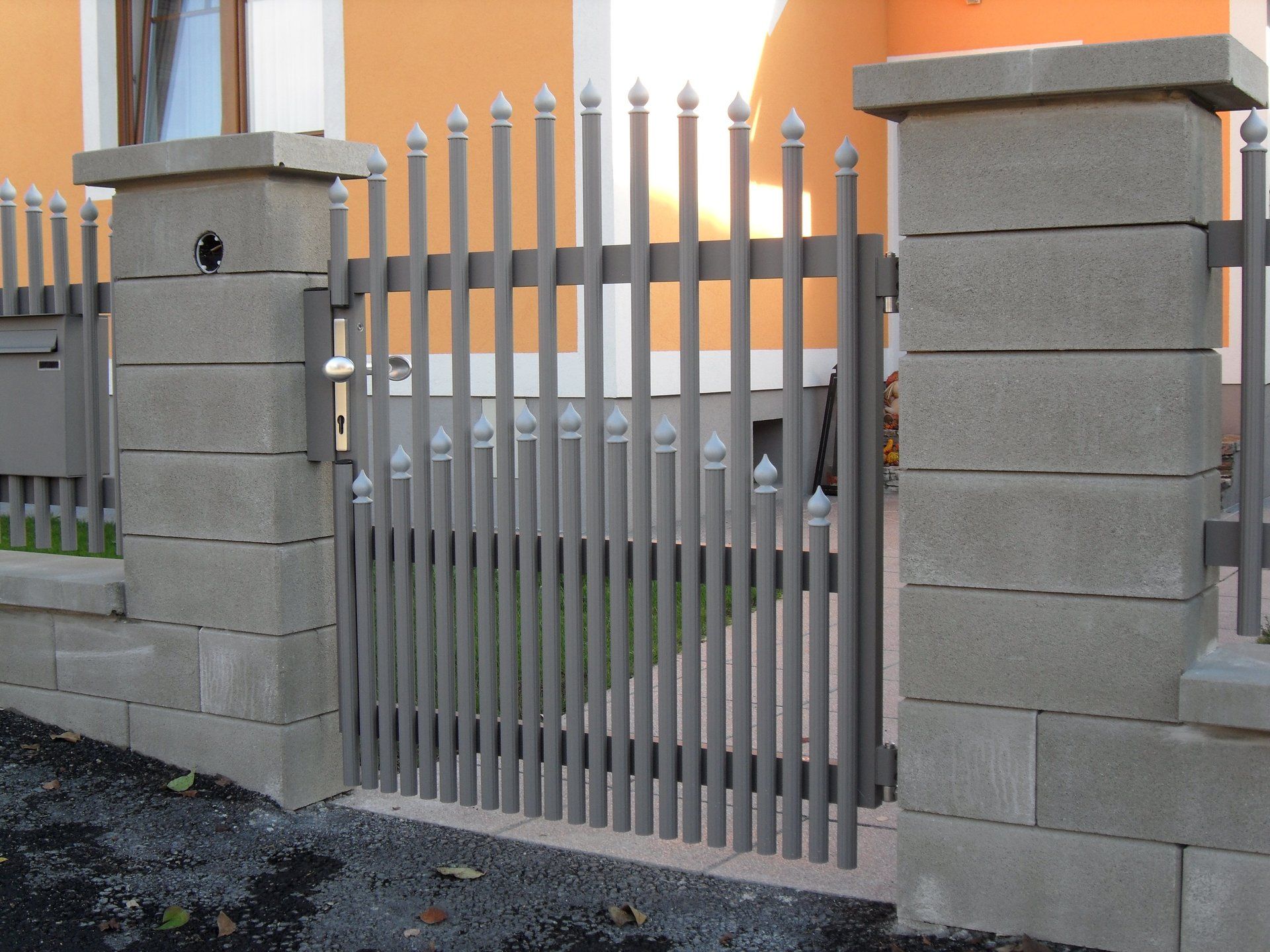 Ein Zaun mit Säulen und einem Tor vor einem Haus