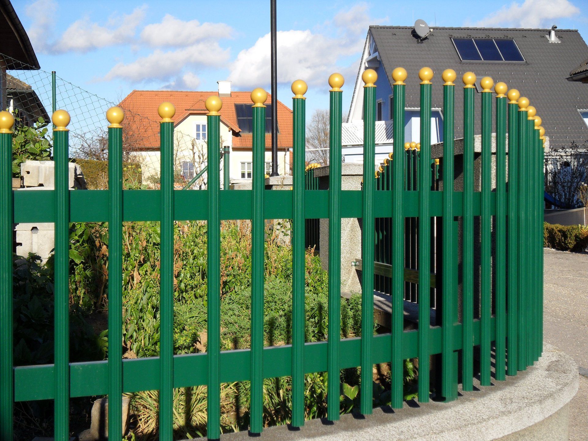 Ein grüner Zaun mit einem Haus im Hintergrund