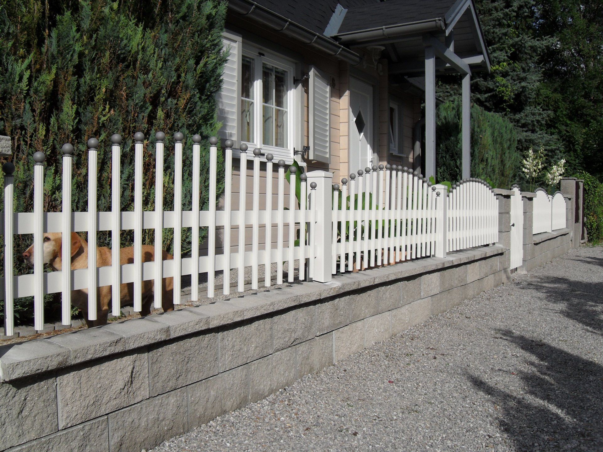 Ein weißer Lattenzaun steht vor einem Haus