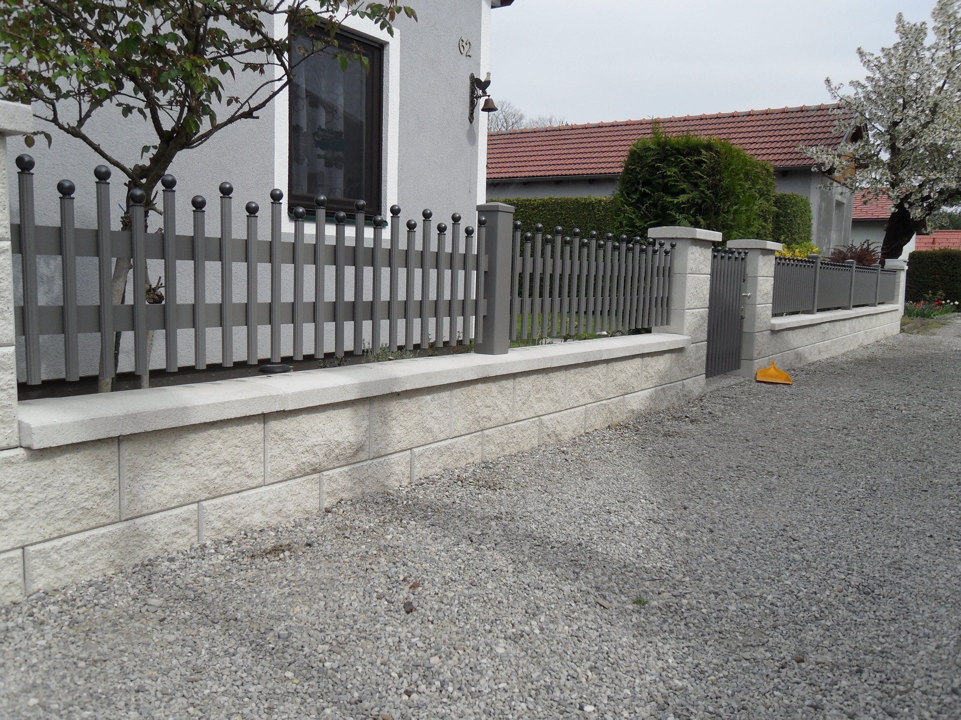 Ein Zaun umgibt eine Kiesauffahrt vor einem Haus