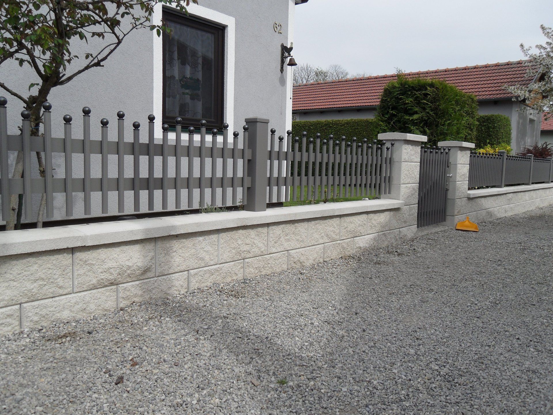 Ein Haus mit einem Zaun und Kies davor