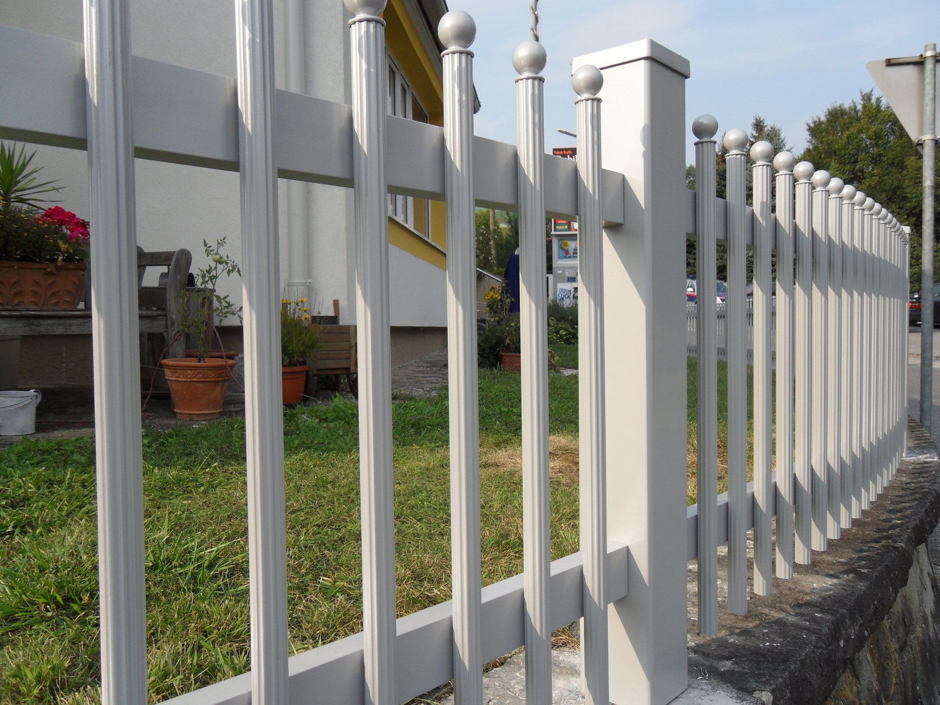 Ein weißer Zaun umgibt einen üppigen grünen Hof vor einem Haus