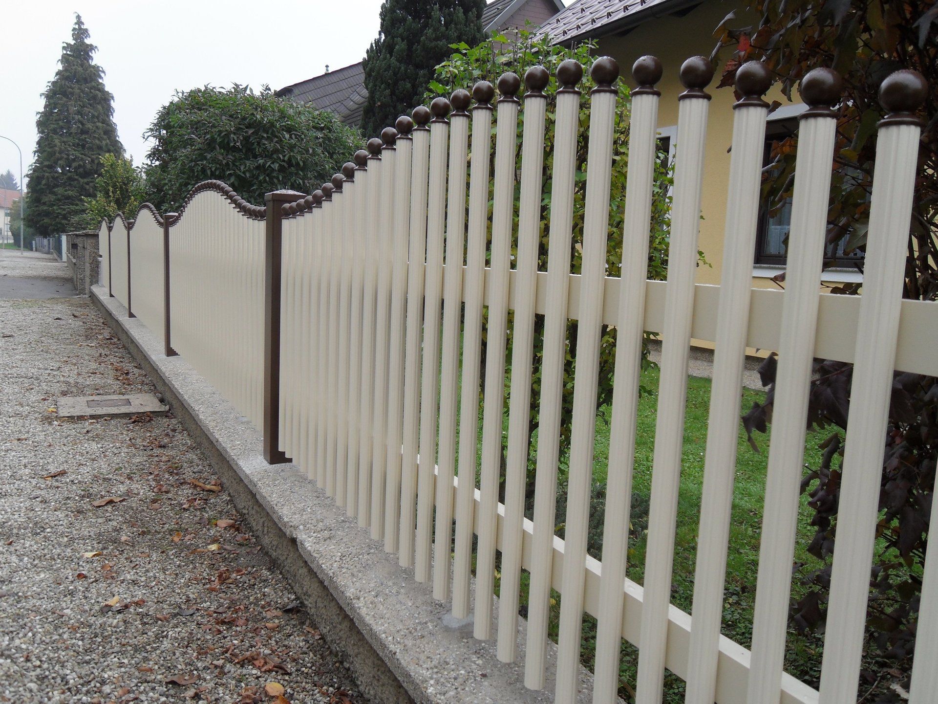 Ein weißer Lattenzaun entlang einer Schotterstraße