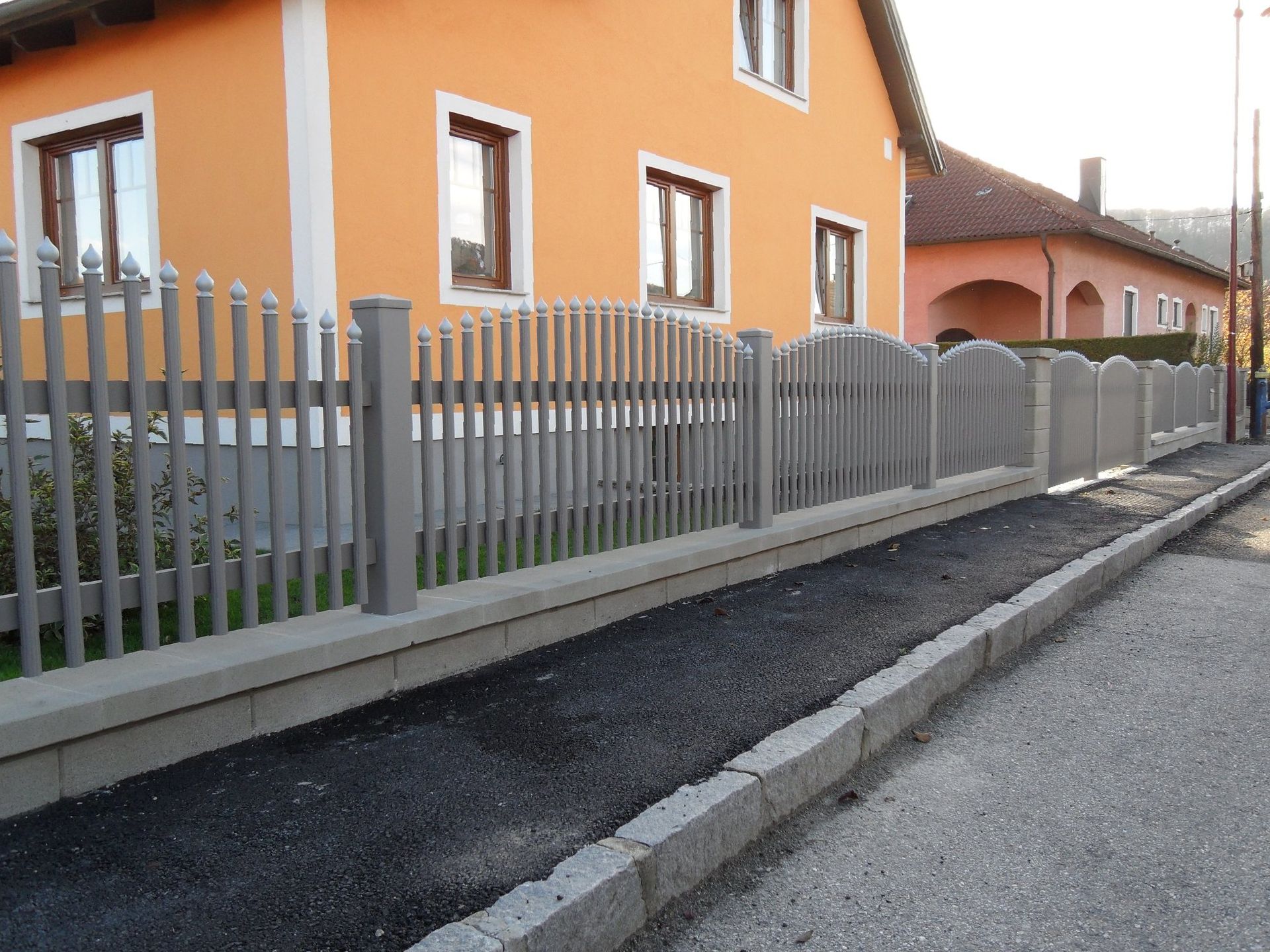 Ein orangefarbenes Haus mit einem Zaun davor