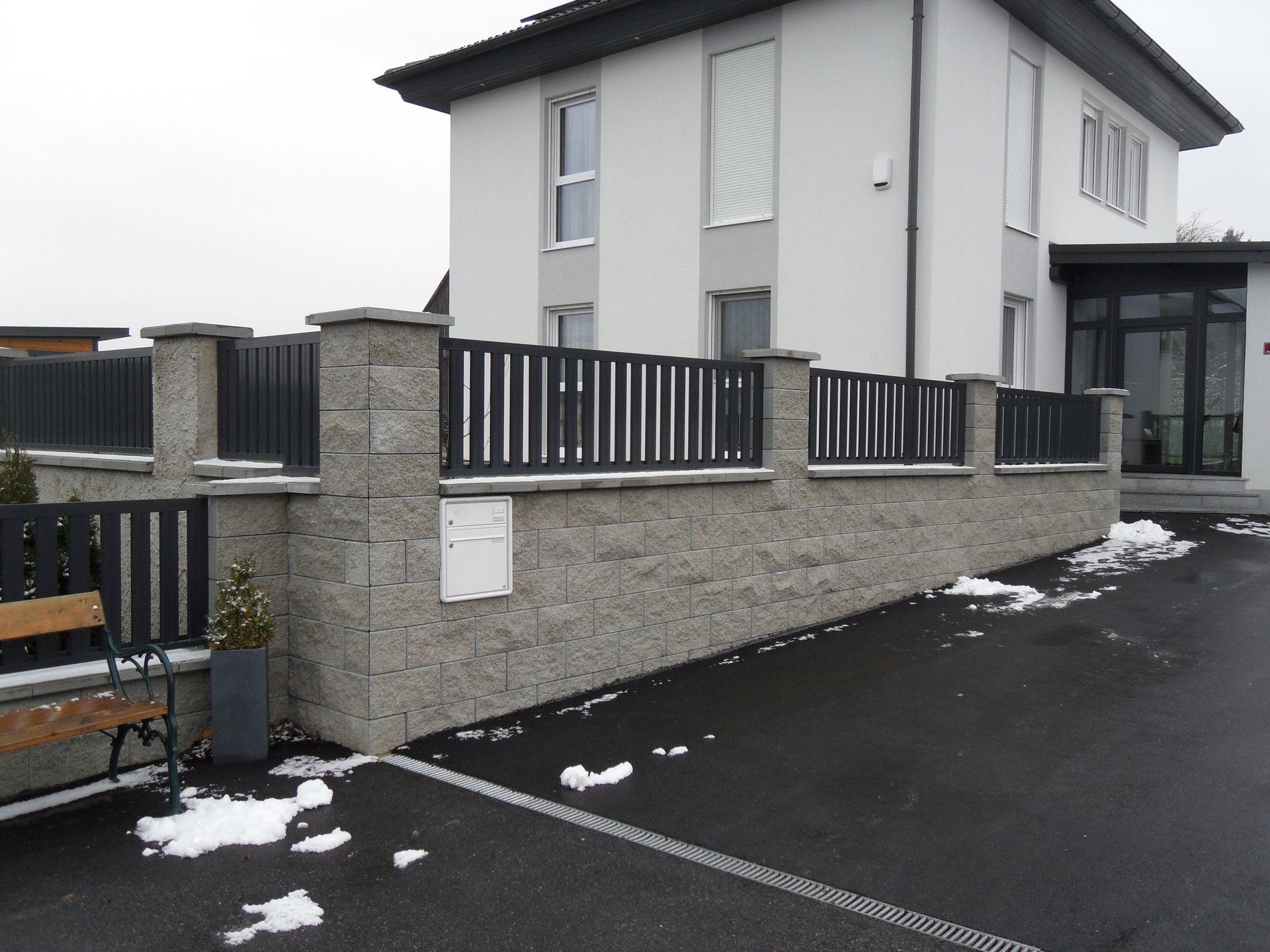 Ein weißes Haus mit einem schwarzen Zaun und einem Briefkasten