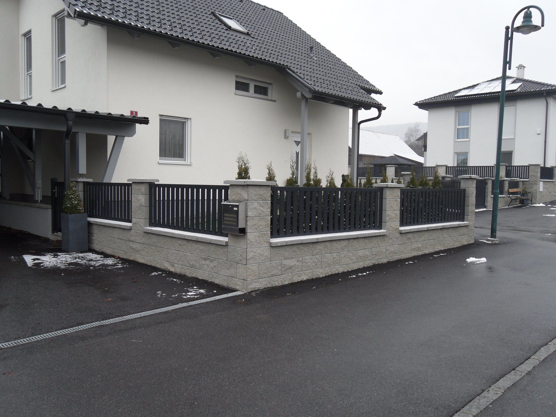 Ein weißes Haus mit einem schwarzen Zaun davor