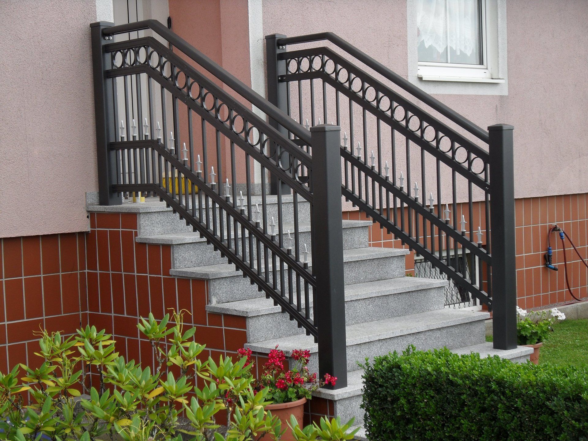 Eine Treppe, die zu einem Haus mit einem schwarzen Geländer führt