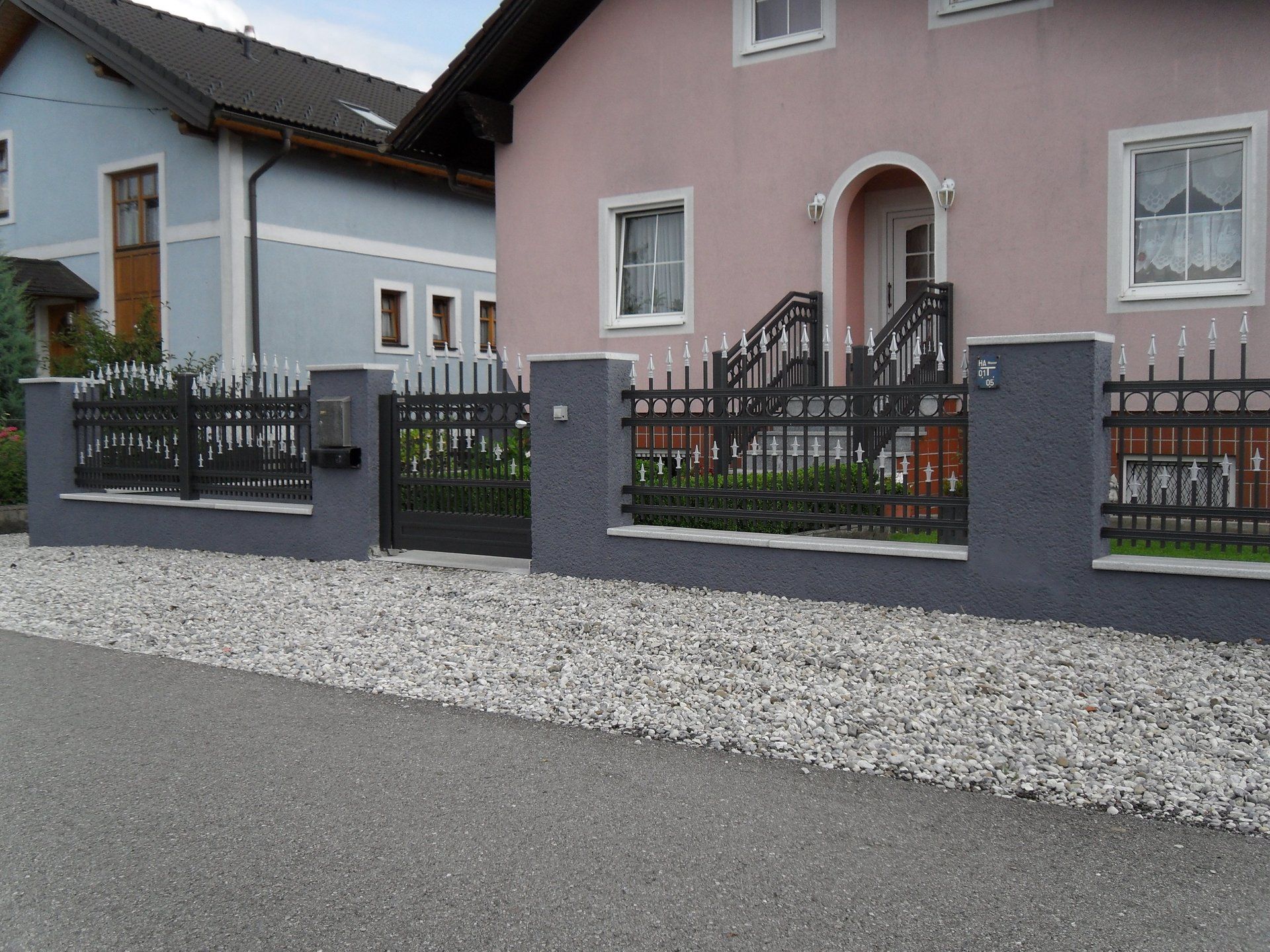 Ein rosa Haus mit einem schwarzen Zaun davor