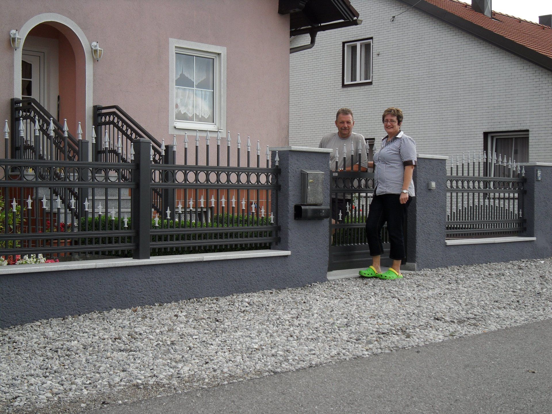 Ein Mann und eine Frau stehen vor einem rosa Haus
