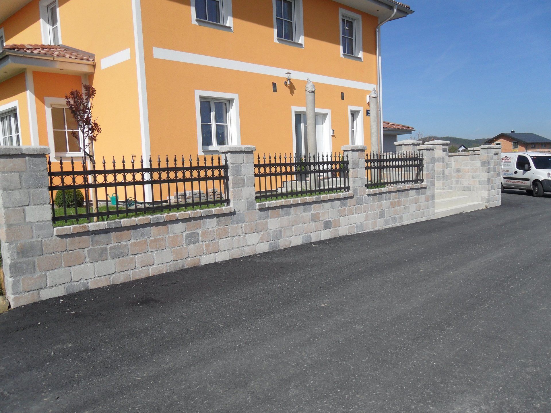 Ein weißer Lieferwagen steht vor einem orangefarbenen Haus