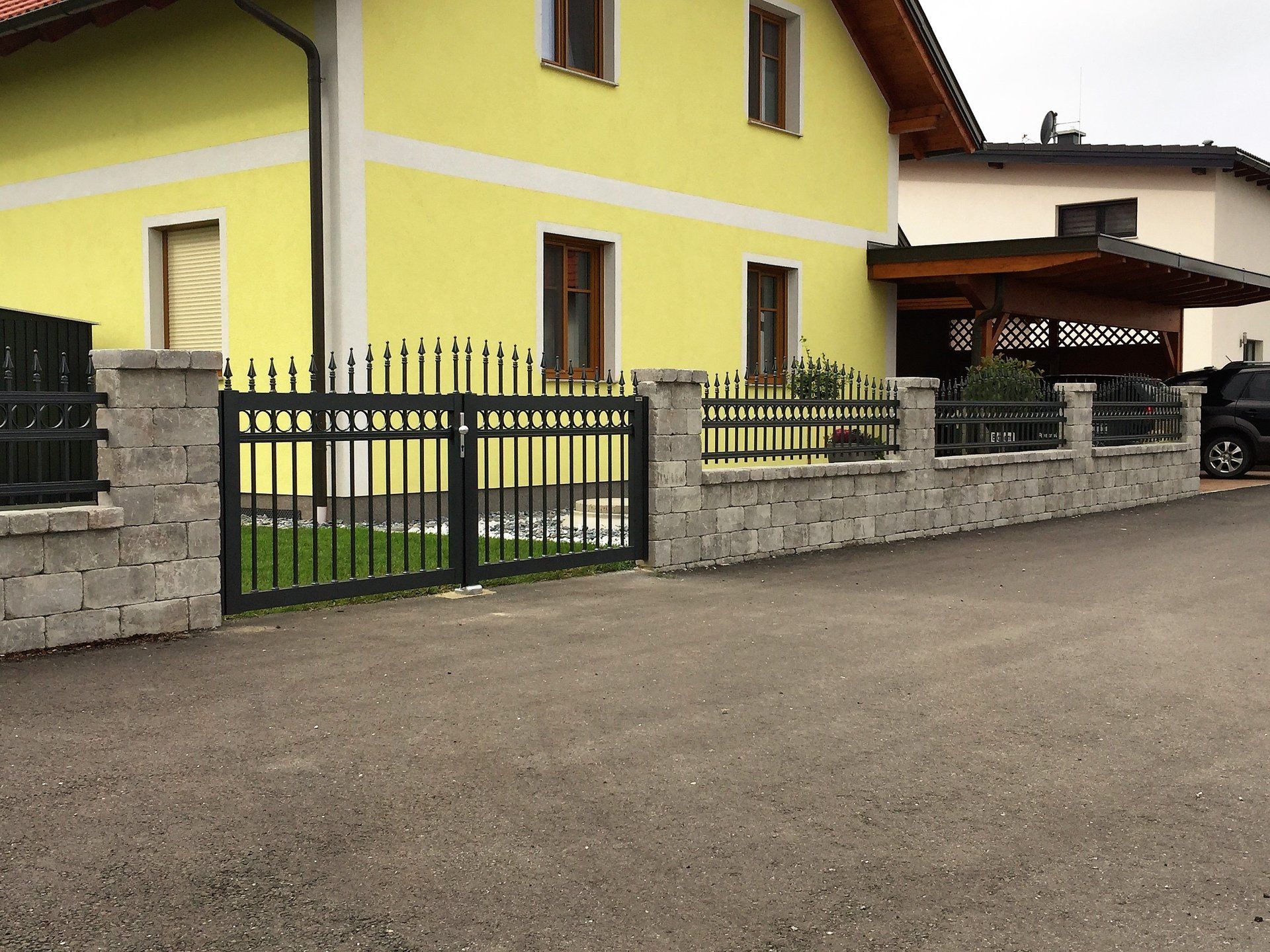 Ein gelbes Haus mit einem schwarzen Zaun davor