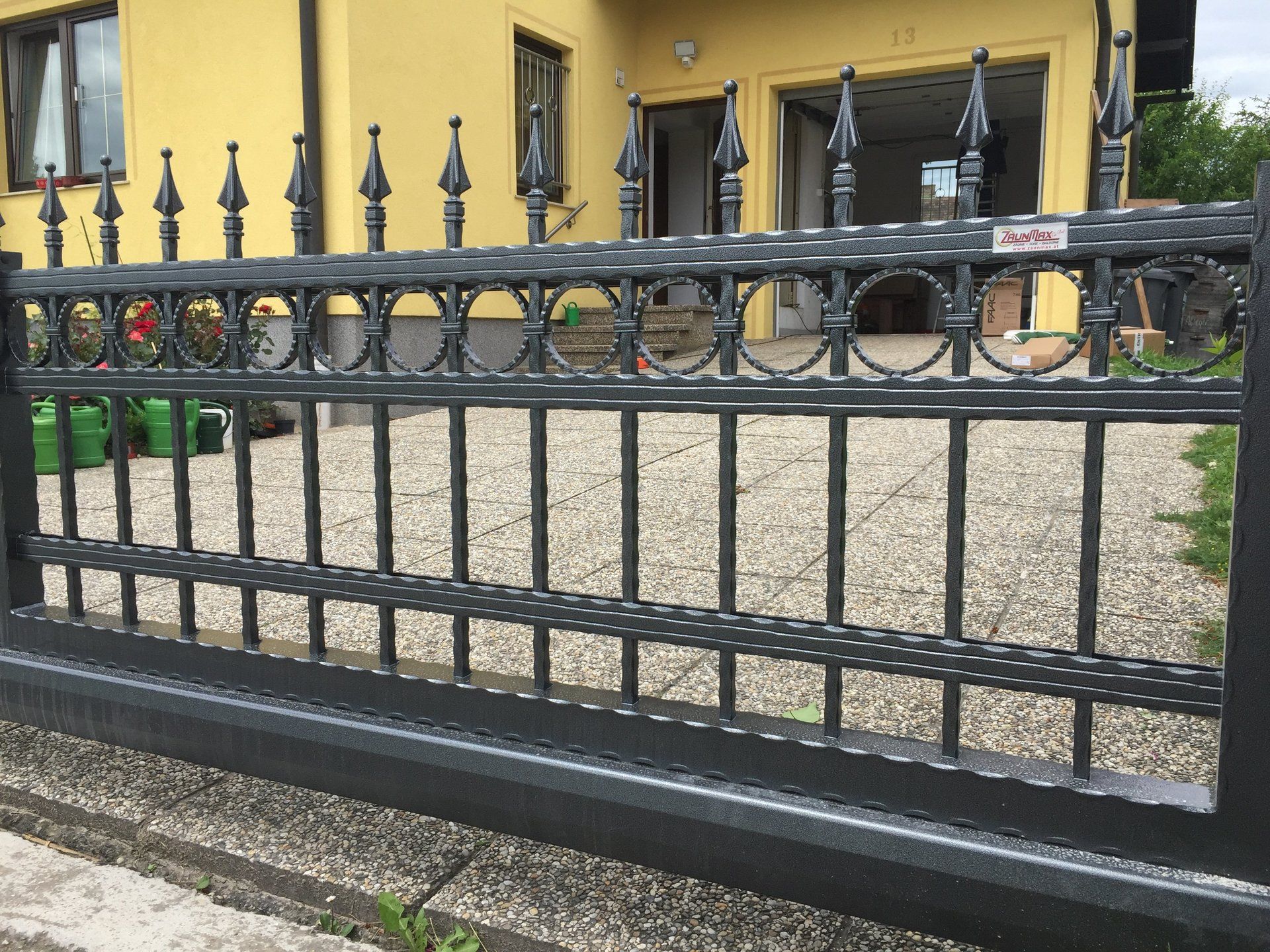 Ein gelbes Haus mit einem schwarzen Zaun davor