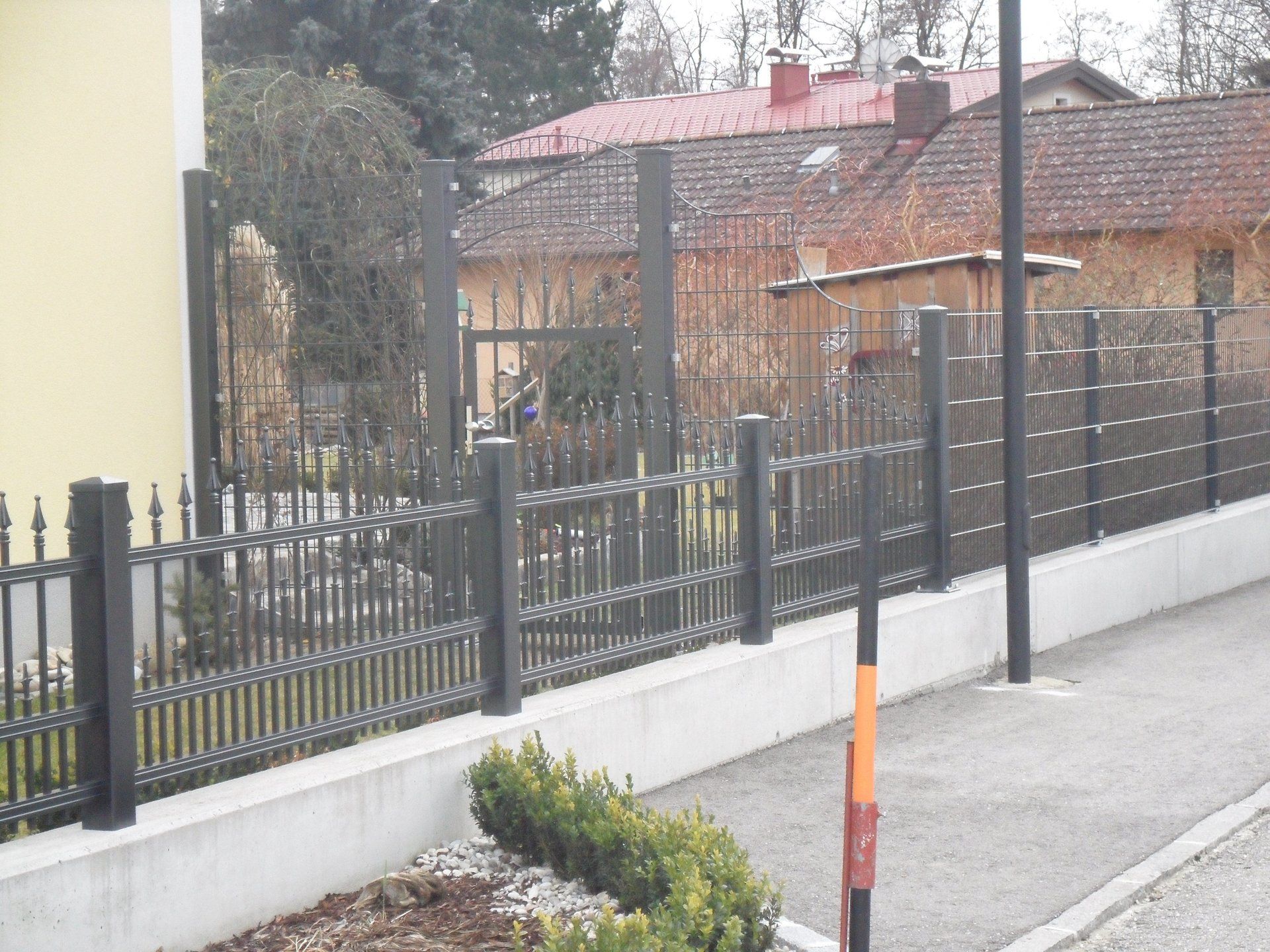 Ein Zaun mit einem gelben Haus im Hintergrund