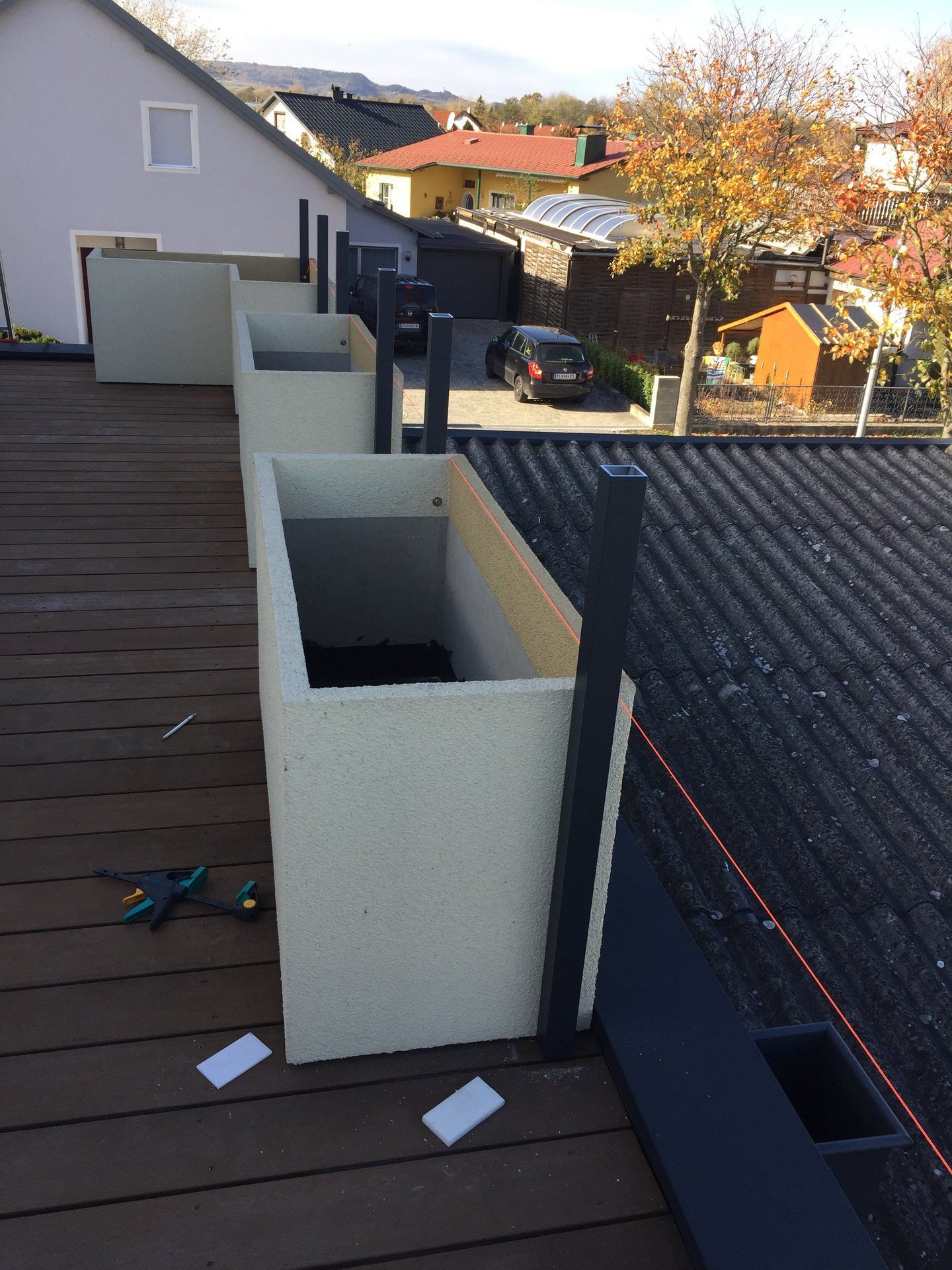 Eine Reihe von Pflanzgefäßen steht auf einem Holzdeck