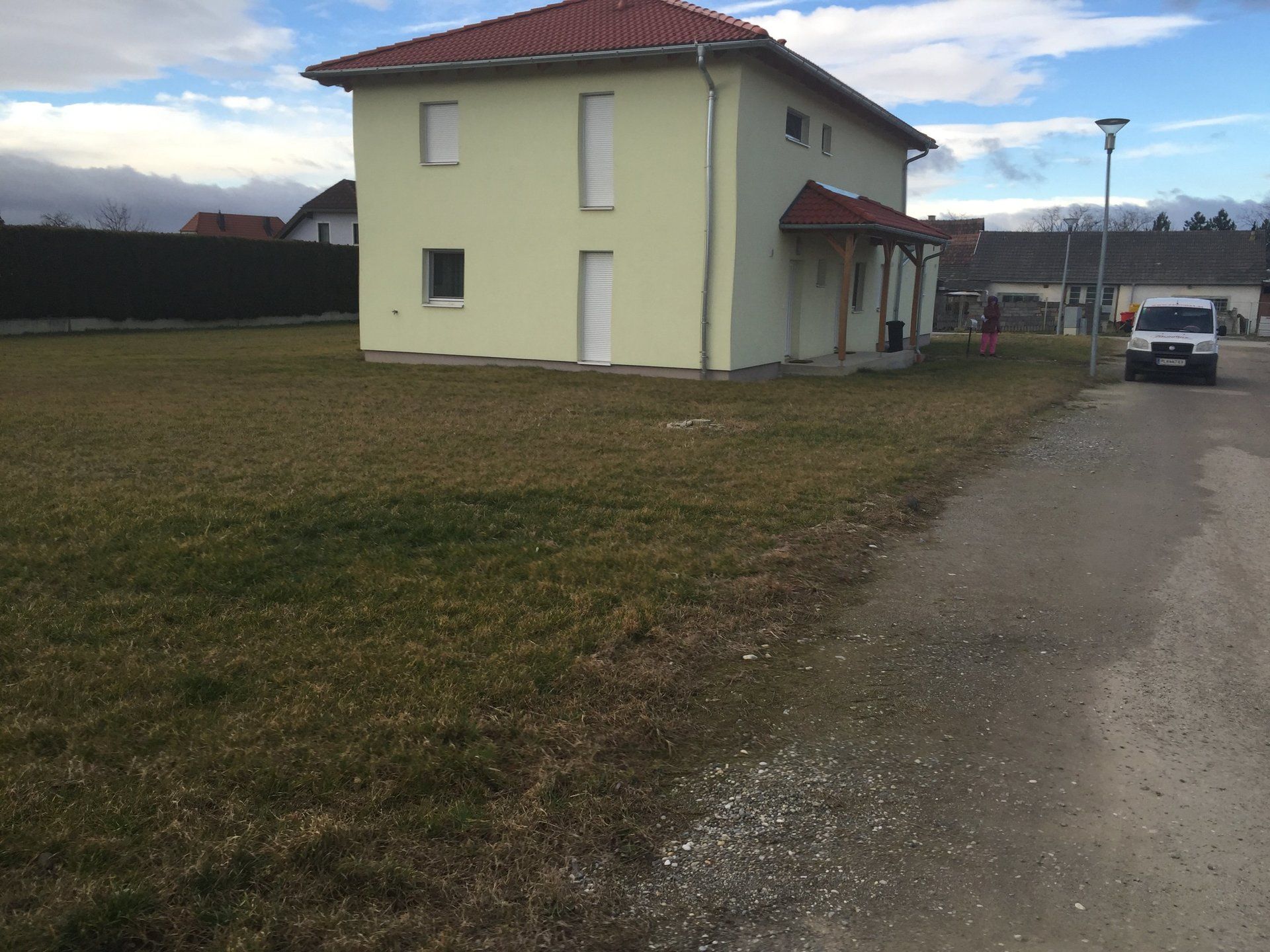 Ein weißer Lieferwagen steht vor einem gelben Haus