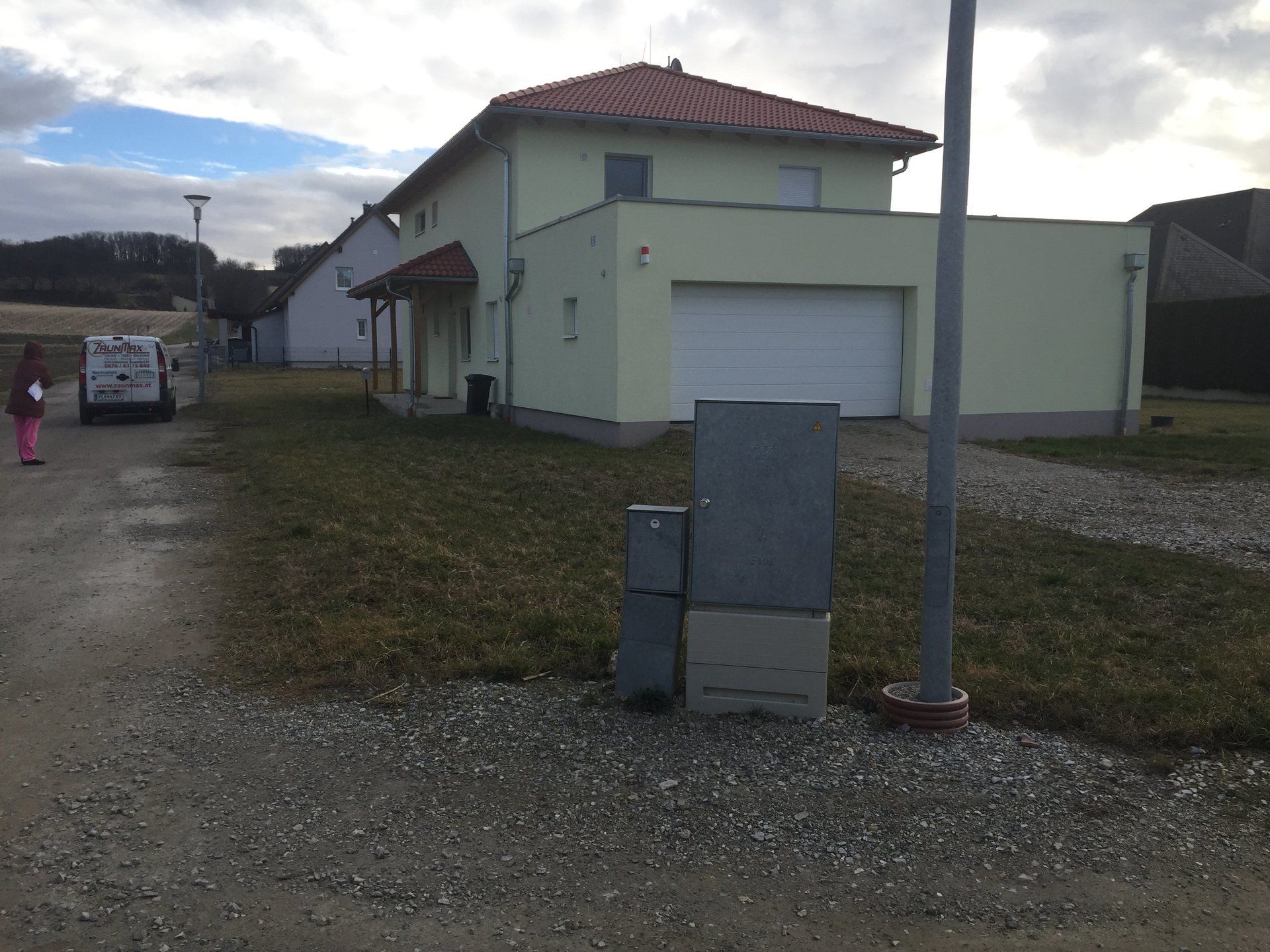 Ein Haus mit einem weißen Garagentor und einem roten Ziegeldach