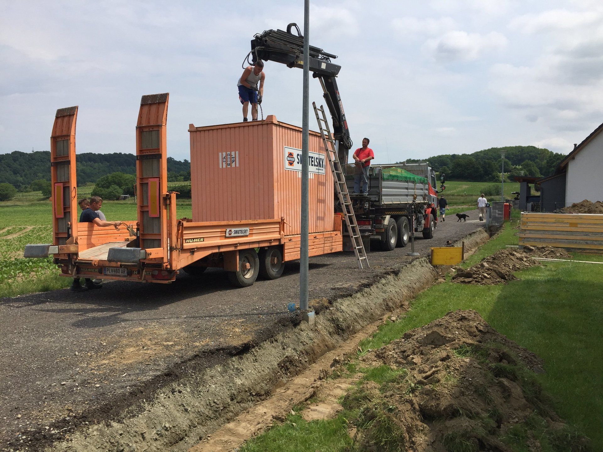 Ein Mann steht auf einem Anhänger, an dem ein Kran befestigt ist.