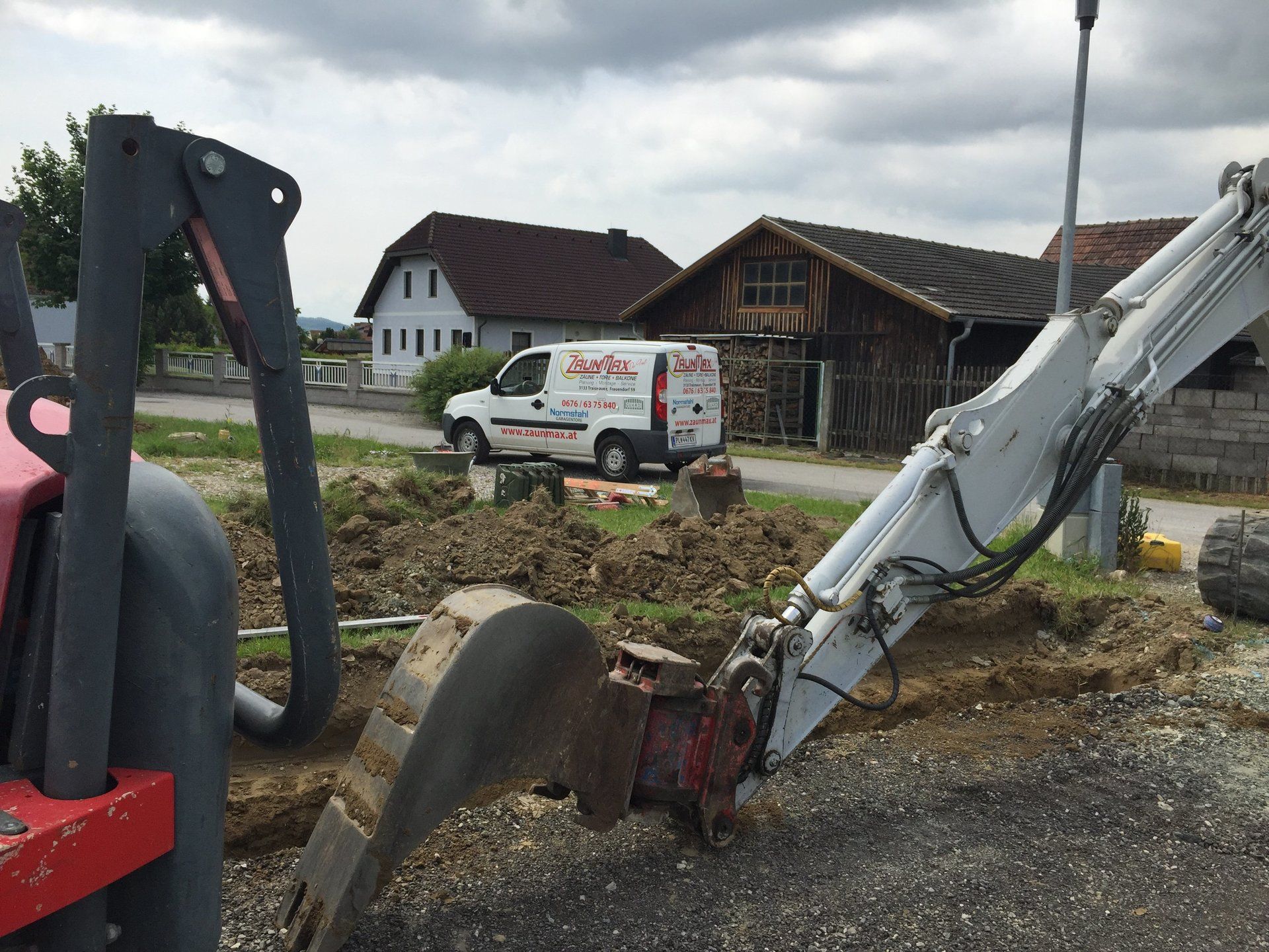 Ein weißer Lieferwagen steht vor einem Baufahrzeug