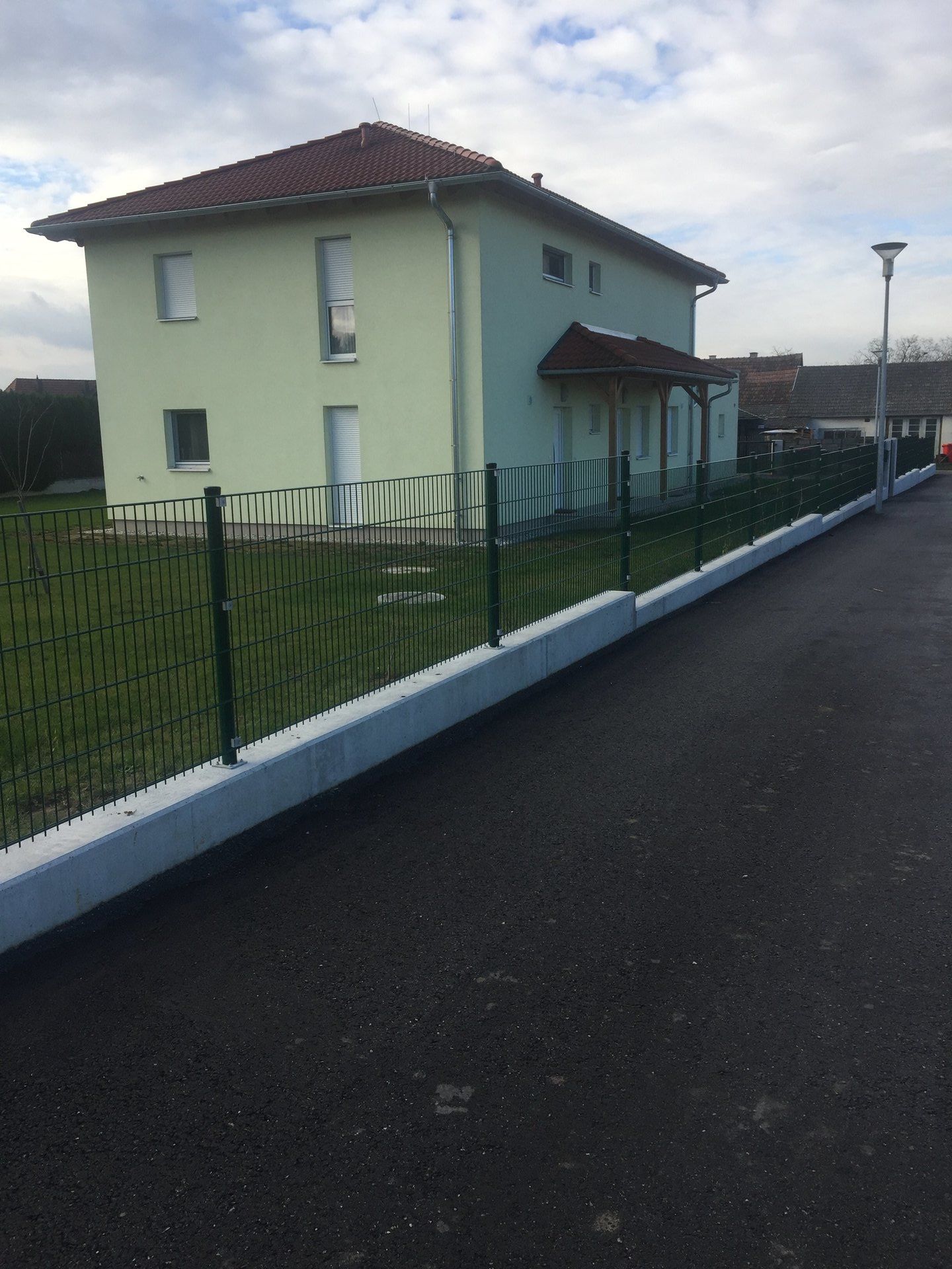 Ein Haus mit einem grünen Dach und einem Zaun darum