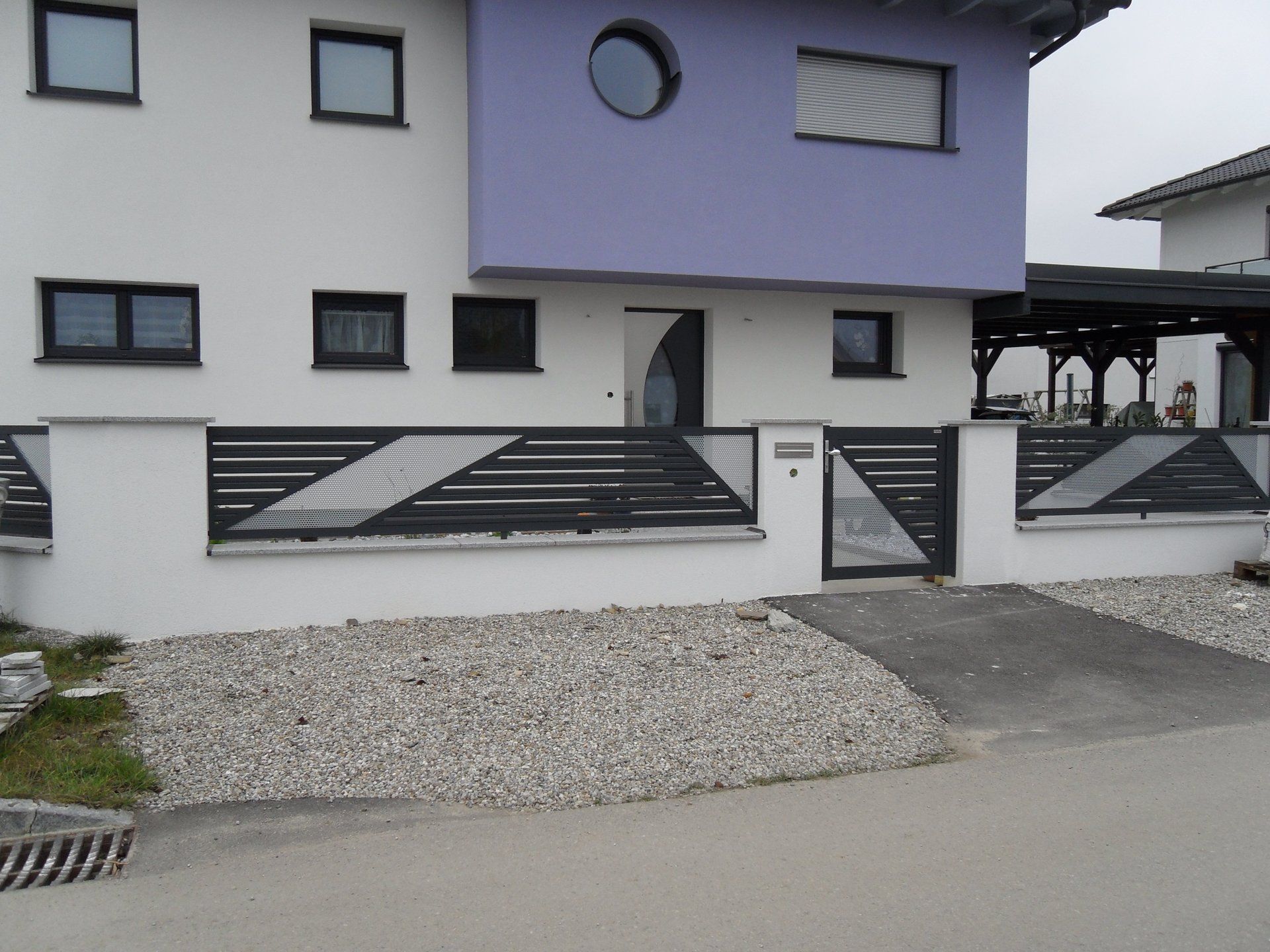 Ein weißes Haus mit einem violetten Dach und einem schwarzen Zaun