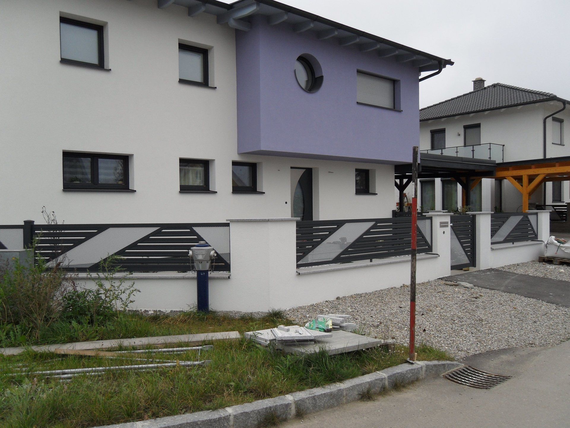 Ein weiß-lila Haus mit einem Zaun davor