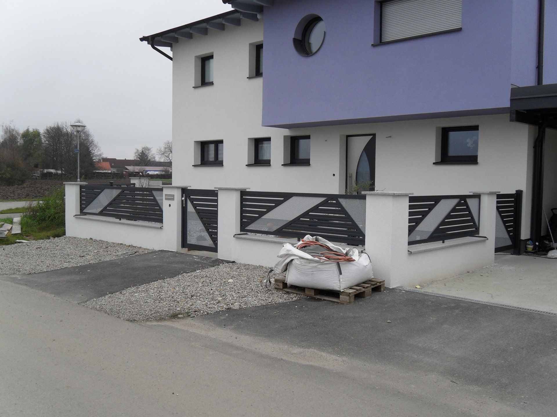 Ein weißes Gebäude mit einem violetten Dach und einem schwarzen Zaun