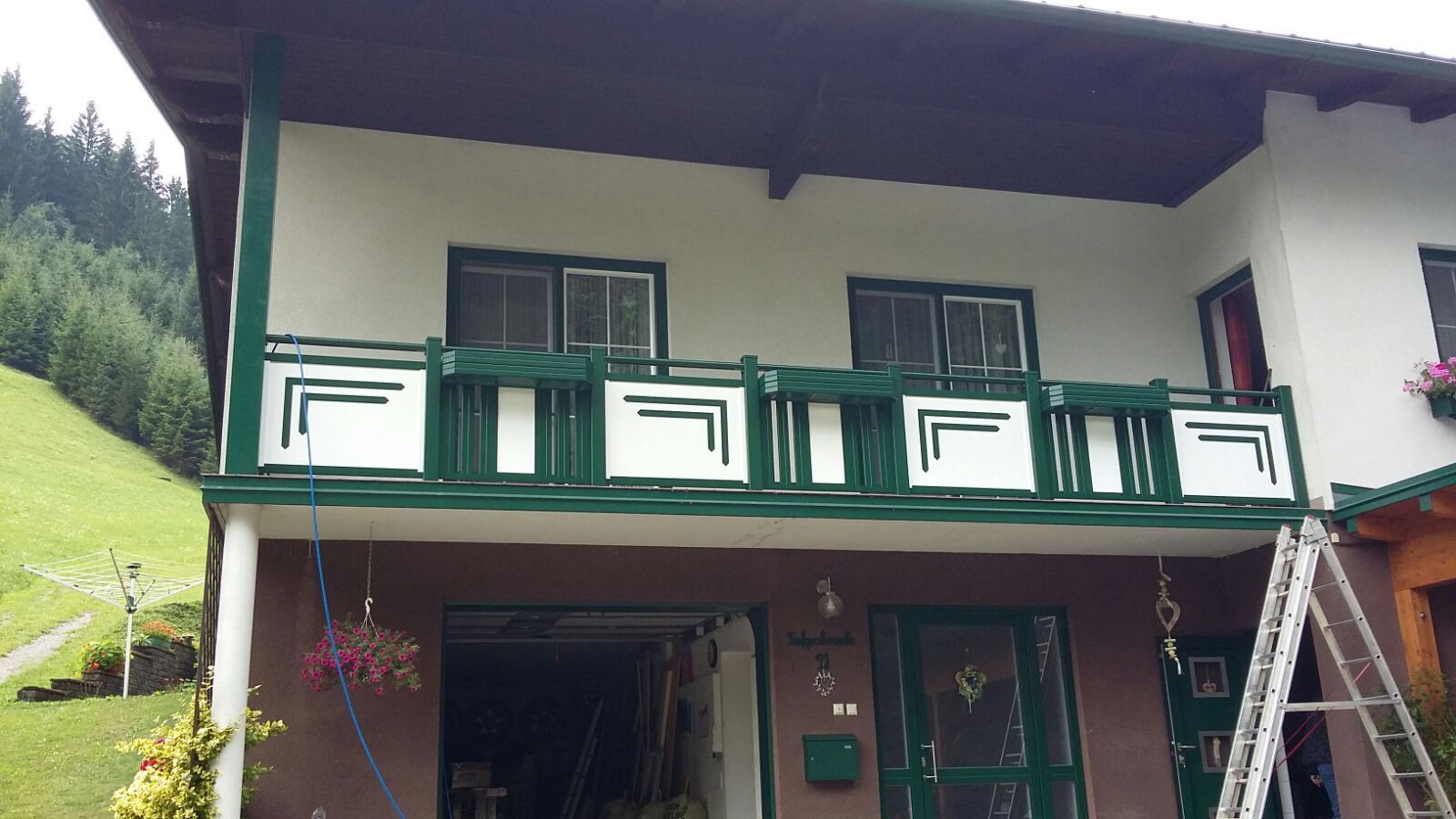 Ein Haus mit einem grünen Balkon und einer Leiter davor