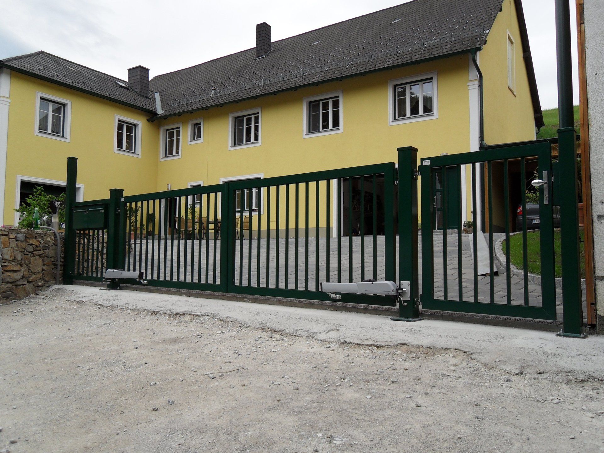 Ein gelbes Haus mit einem grünen Zaun davor